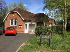 A brick building with a brown roof, a parked red car.