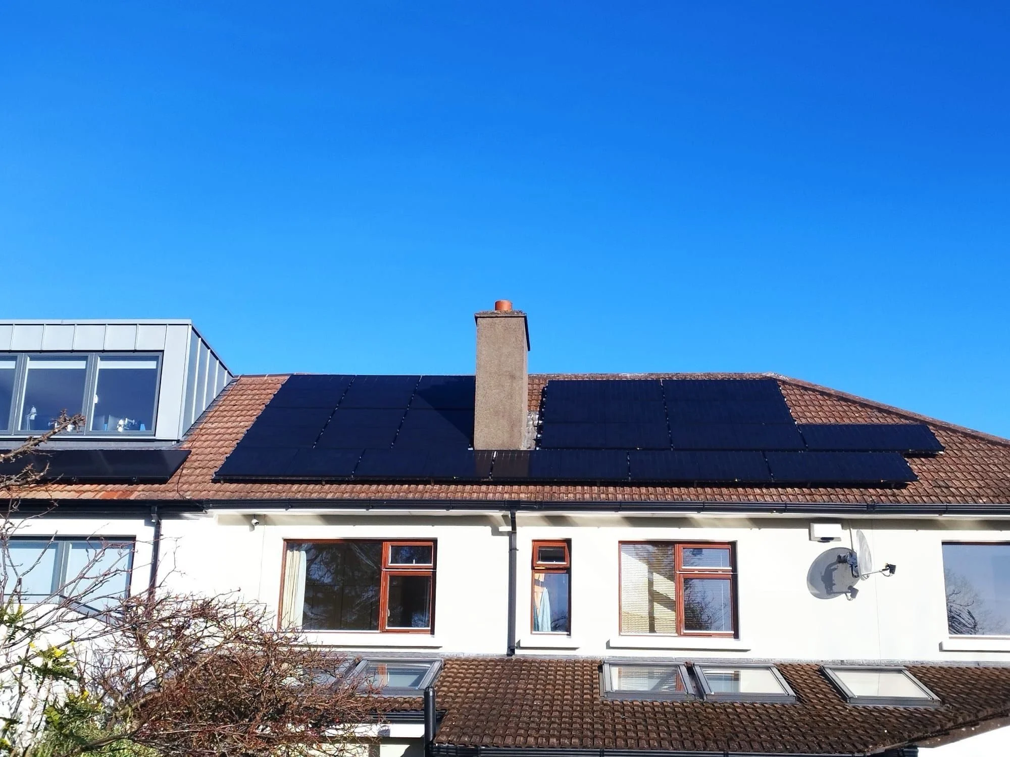 House with solar panels on the roof and a bright blue sky.