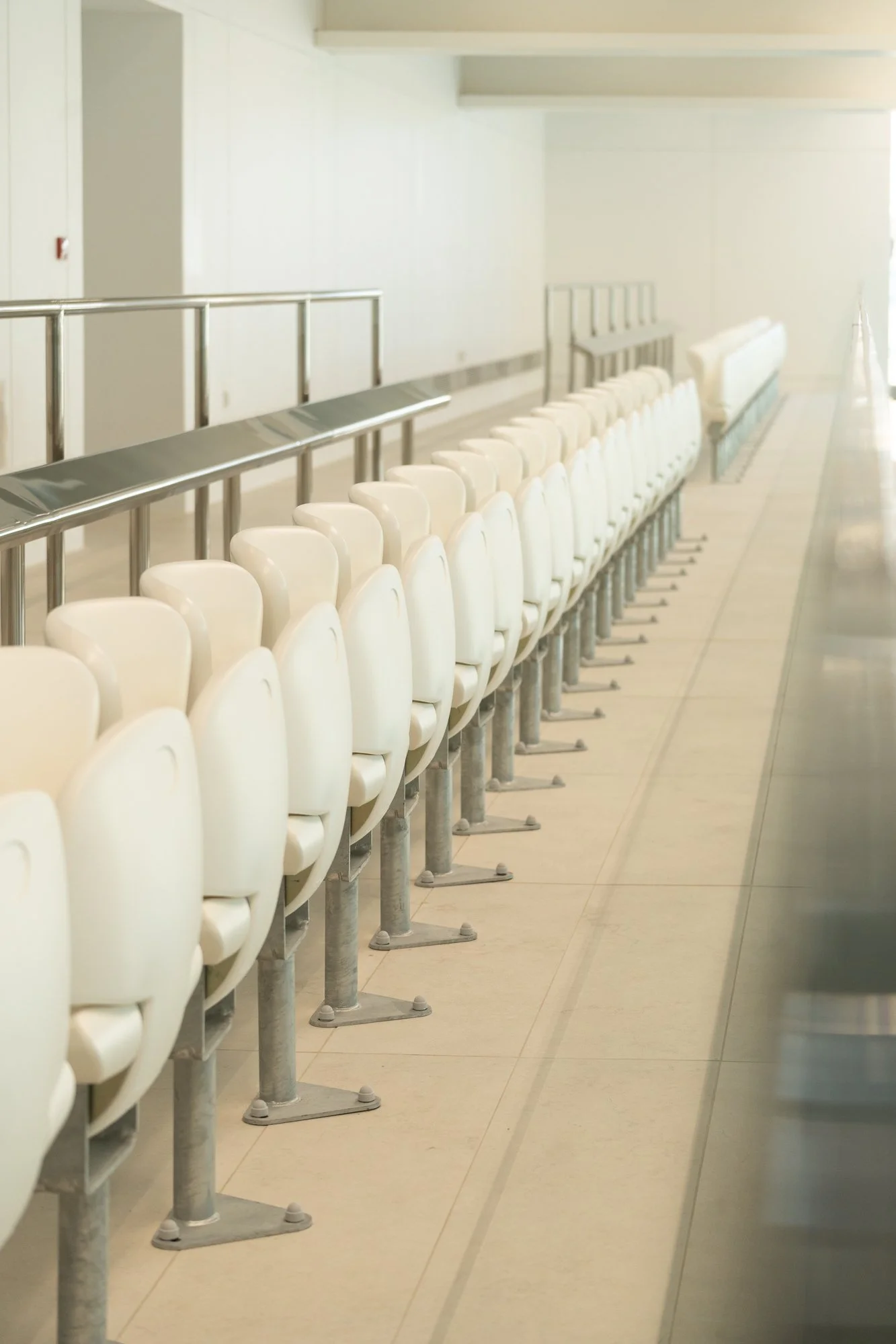 Empty chairs lined up in a row in an airport terminal corridor.