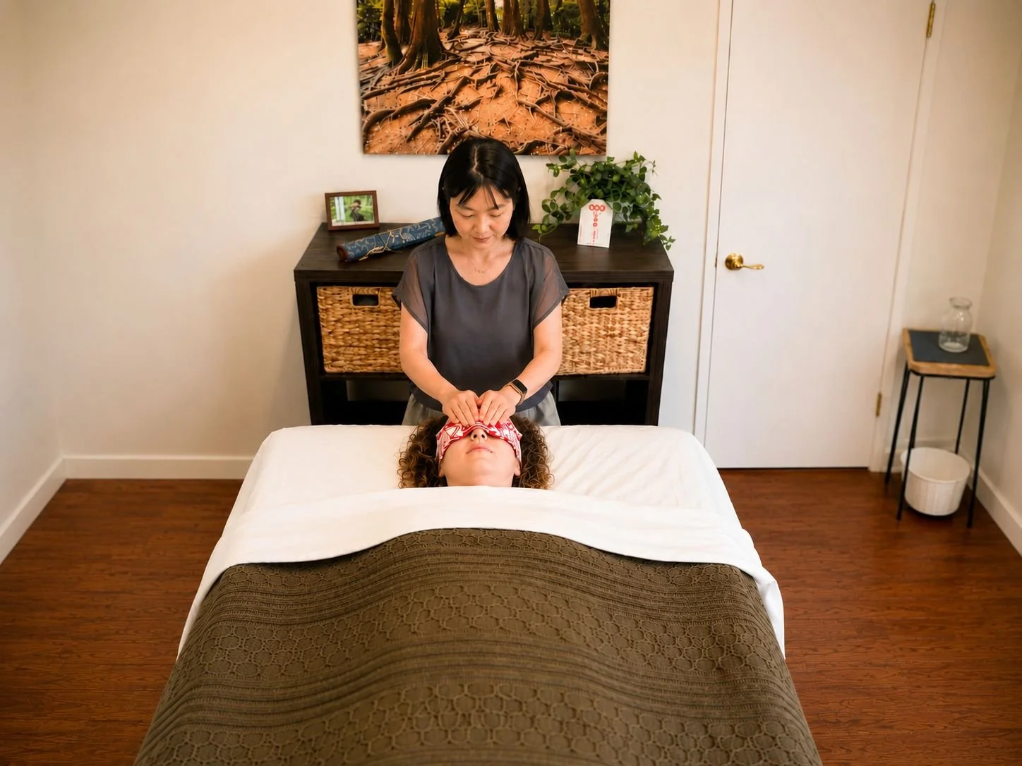 A woman receiving a facial treatment from a massage therapist in a well-lit, cozy room.
