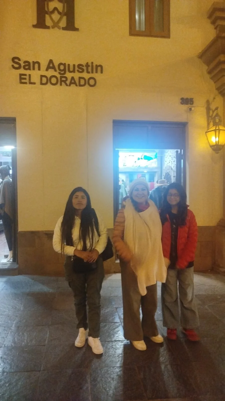 Personas de pie frente a la fachada de un edificio en San Agustín, El Dorado, en la noche.