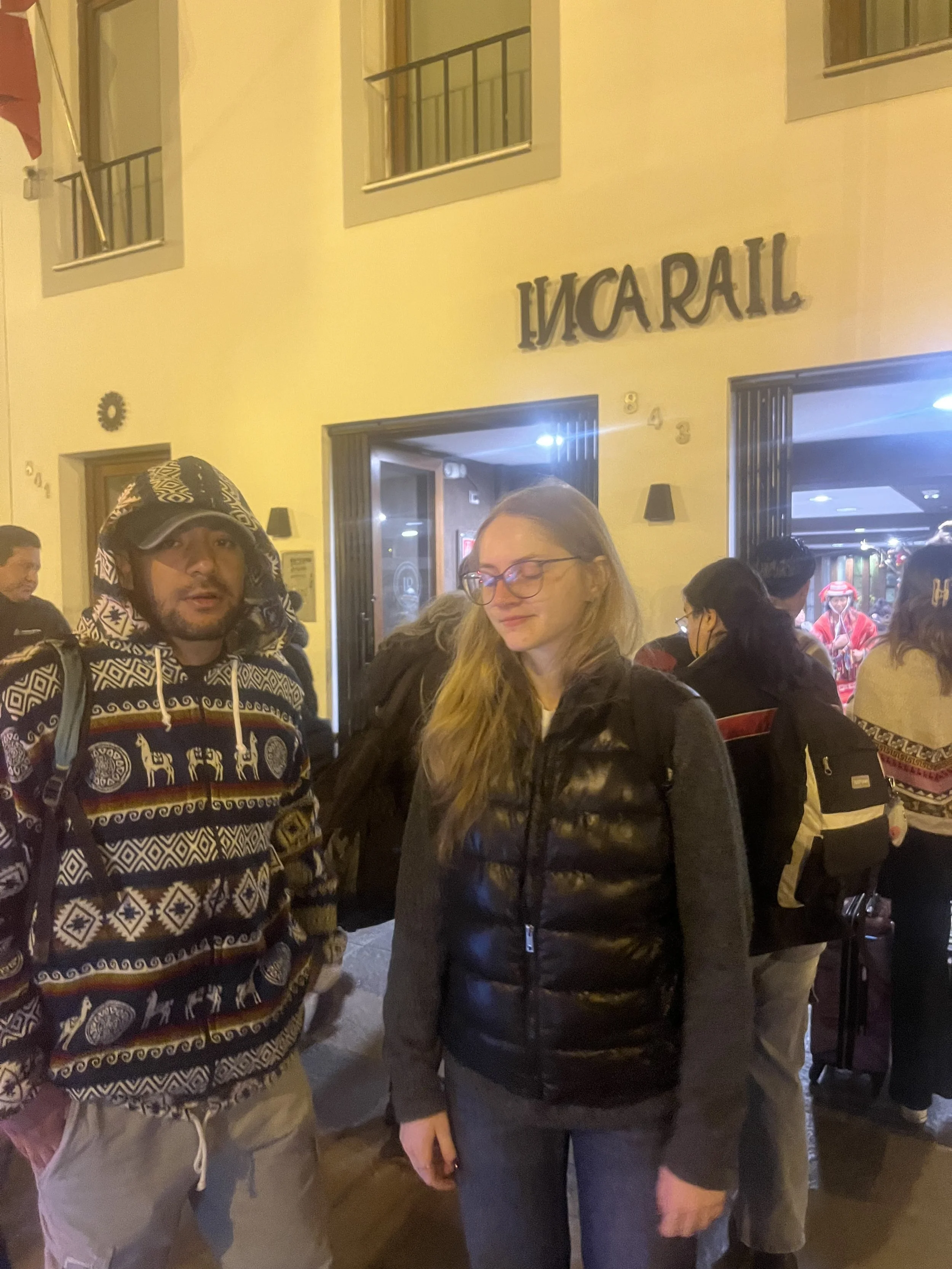 Dos personas en la calle frente a un restaurante llamado 'Inca Rail'.