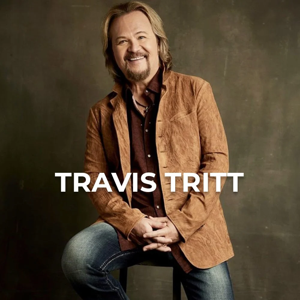 Photo of a man with shoulder-length blond hair, a beard, and mustache, wearing a brown jacket over a dark shirt, sitting on a stool against a brown background, with the text "TRAVIS TRITT" overlayed.