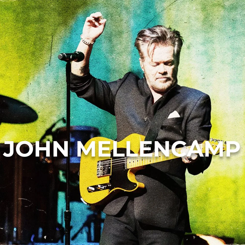 A man in a black suit playing a yellow electric guitar on stage.