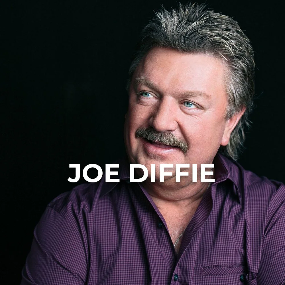 Portrait of Joe Diffie with light-colored hair, mustache, and beard, wearing a purple checkered shirt against a black background.