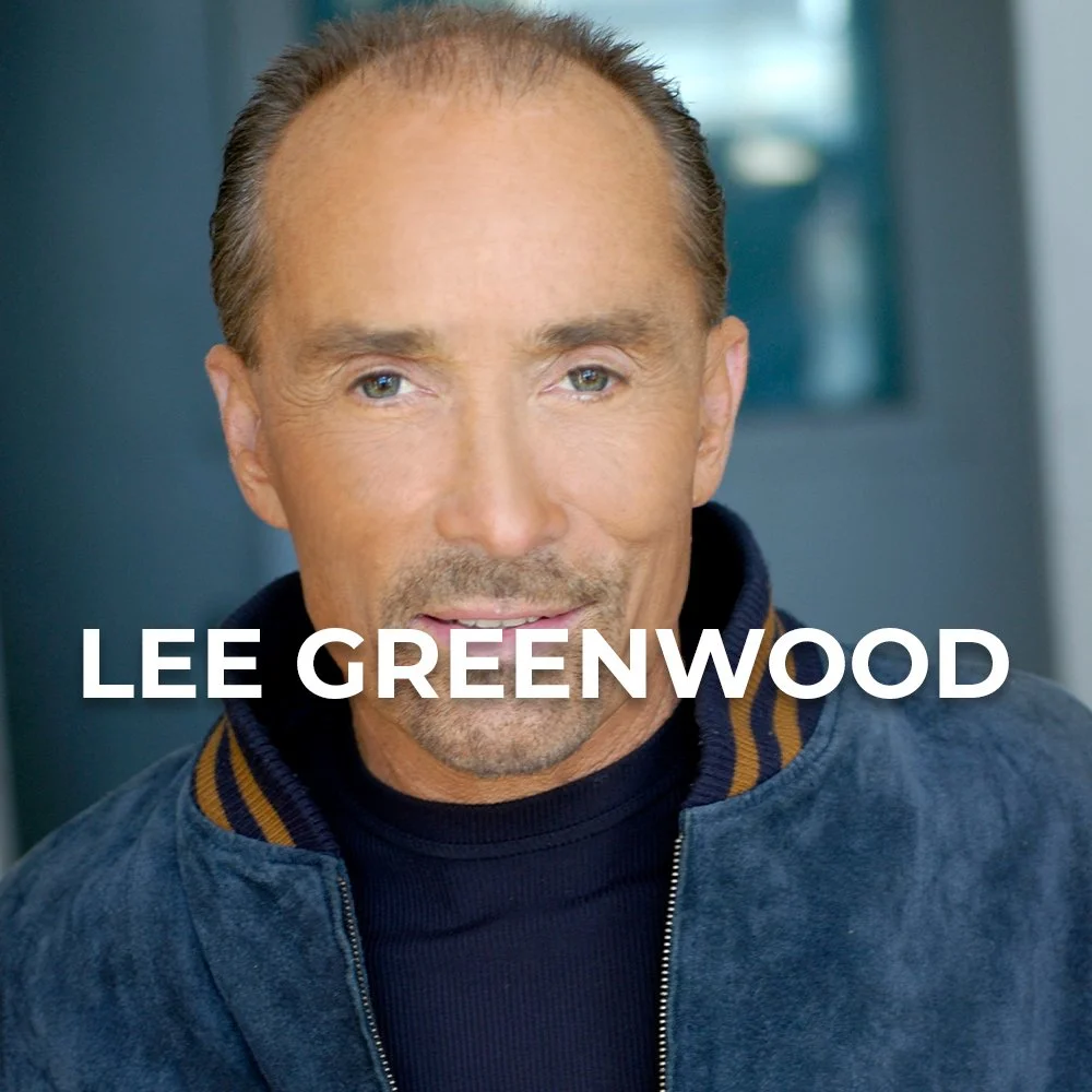Close-up of a man with short brown hair and blue eyes, wearing a navy blue jacket with a tan collar. The background is blurred, and the name 'Lee Greenwood' is displayed in white text over the image.