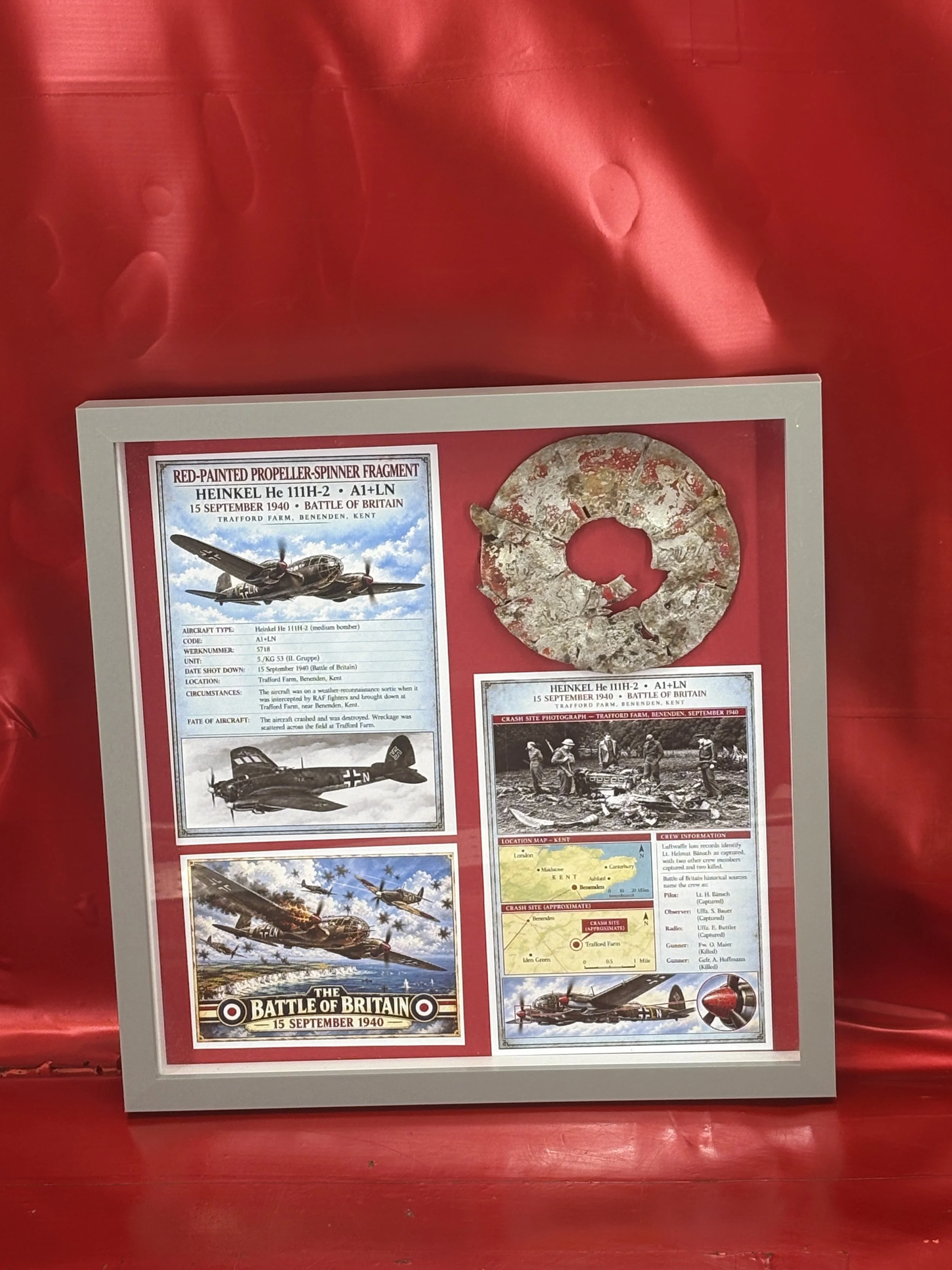 Very rare glass framed red painted propeller spinner fragment recovered from a German Luftwaffe Heinkel He111shot down and made a forced landing at Trafford Farm in Benenden, battle of Britain