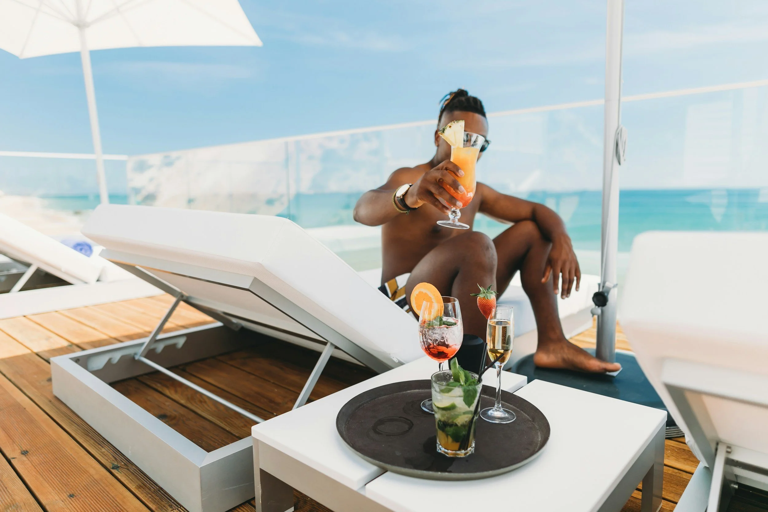 Luxury beach getaway featuring a traveler lounging with tropical drinks by the ocean, captured by Legacy Reserve Travel.
