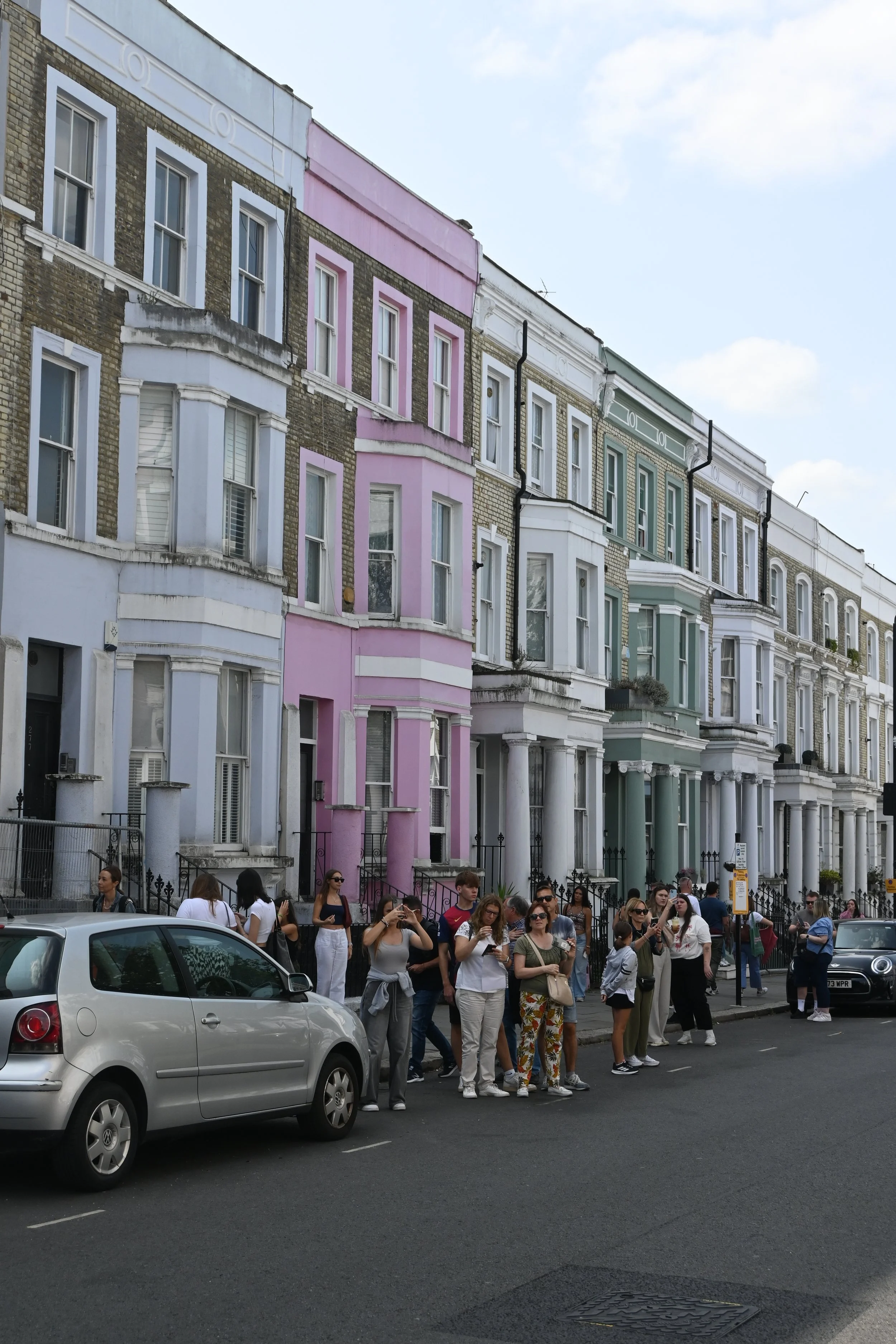 Gruppo di persone in attesa sulla strada davanti a case vittoriane colorate a Londra. Notting Hill a Londra.