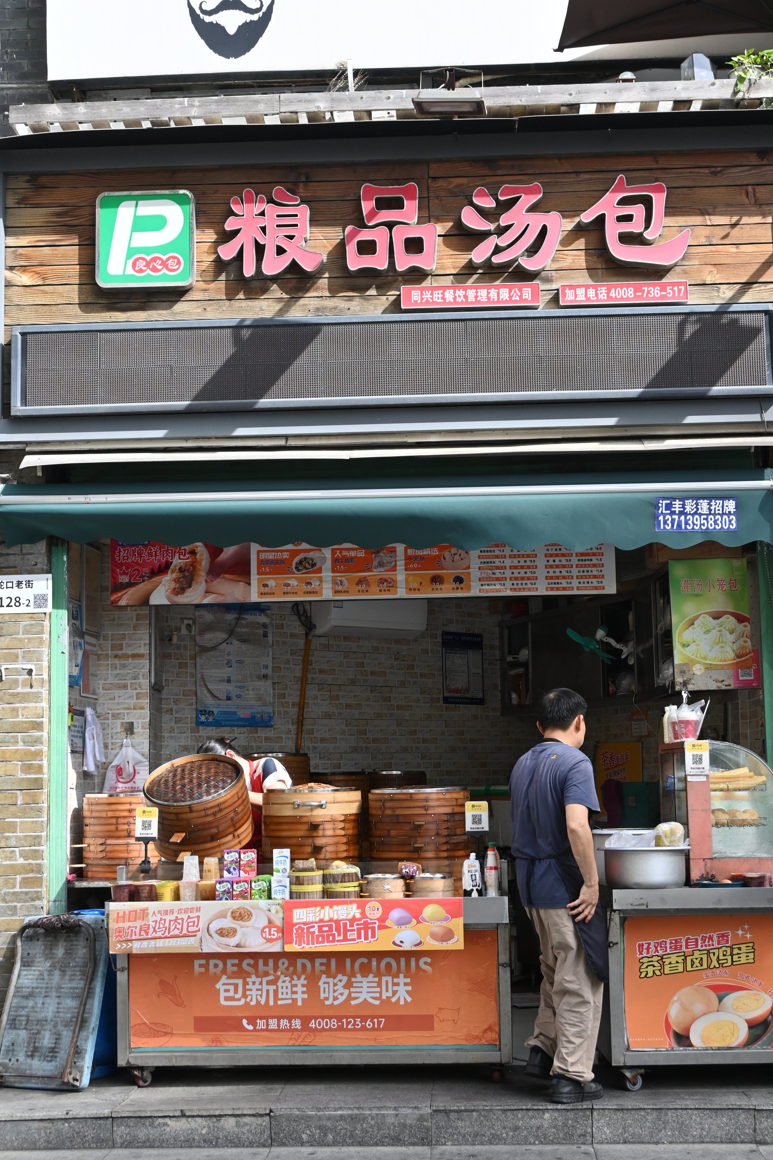 Vendita di alimenti di strada con cestini di bambù, menu con piatti cinesi, venditore dietro il banco e cliente che chiacchiera