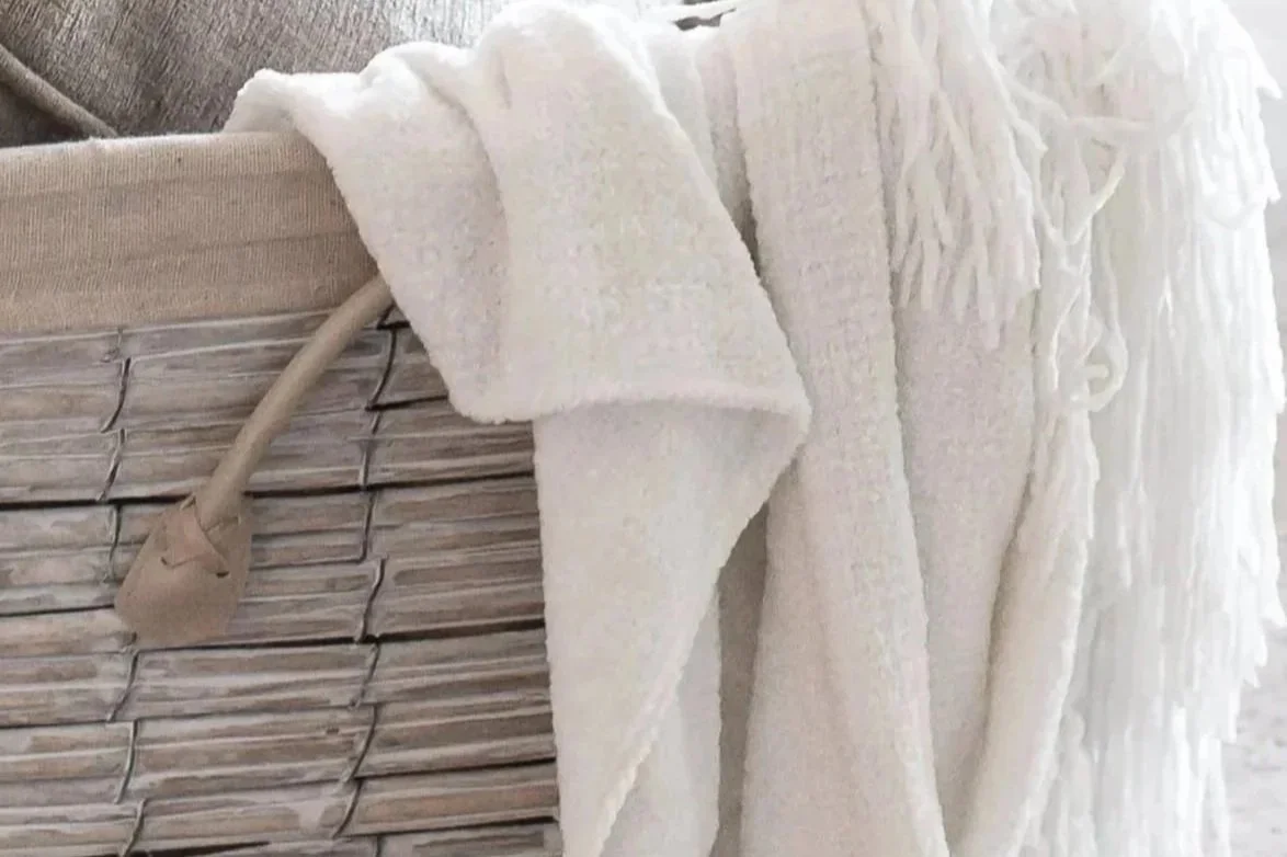 Close-up of a wicker basket with a white towel draped over the edge.