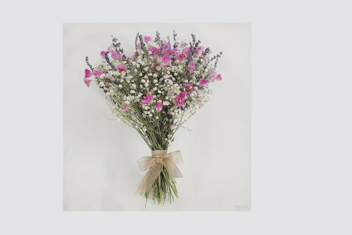 Bouquet of white baby's breath and pink daisies with a beige ribbon tied around the stems.