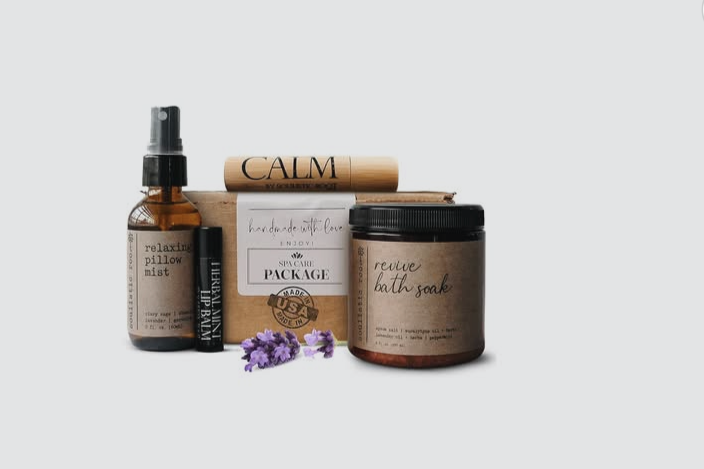 Set of self-care products including a pillow mist, lip balm, bath soak, and a lavender sprig