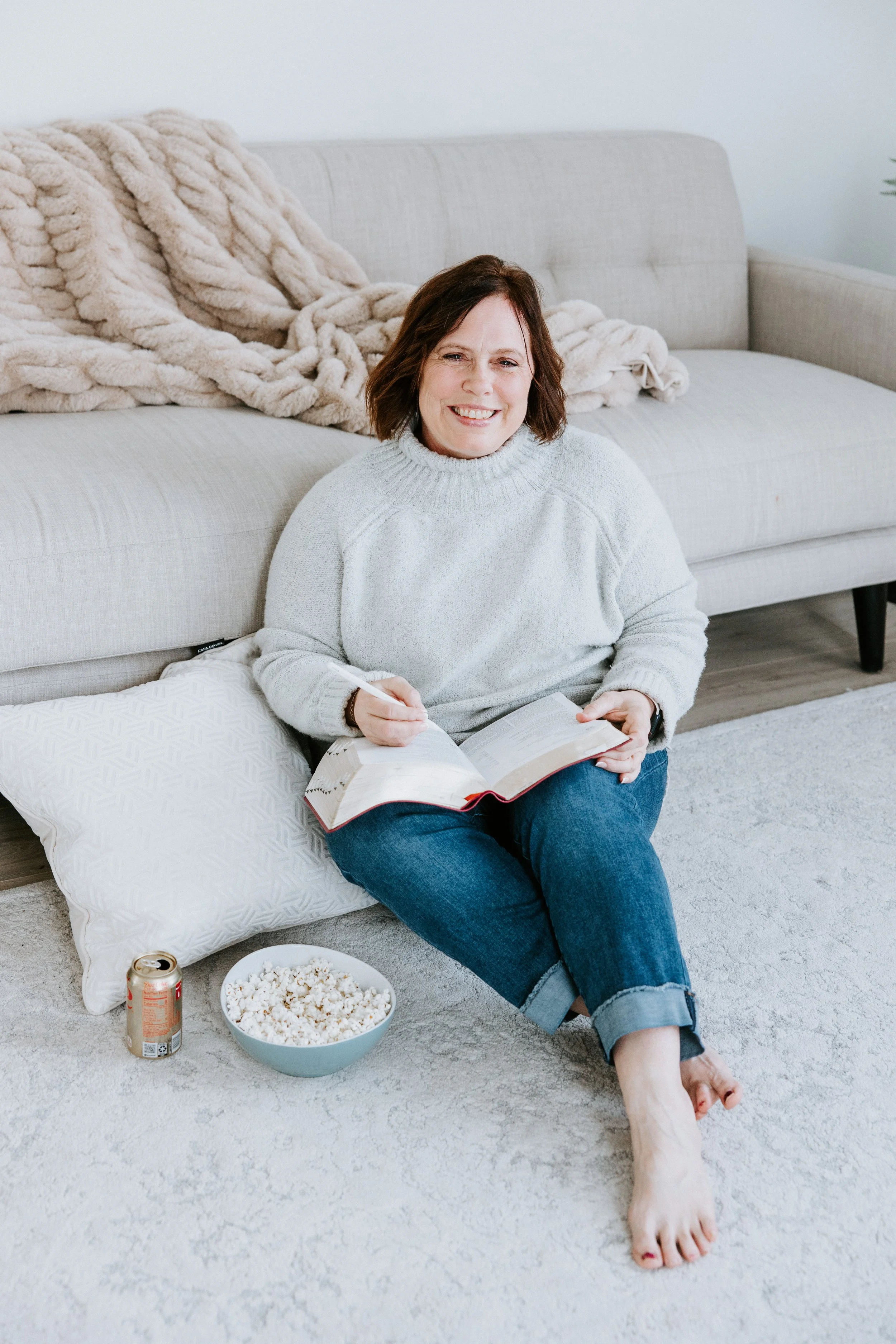 Kim Vander Poel reading her Bible at home on floor in front of couch with popcorn nearby