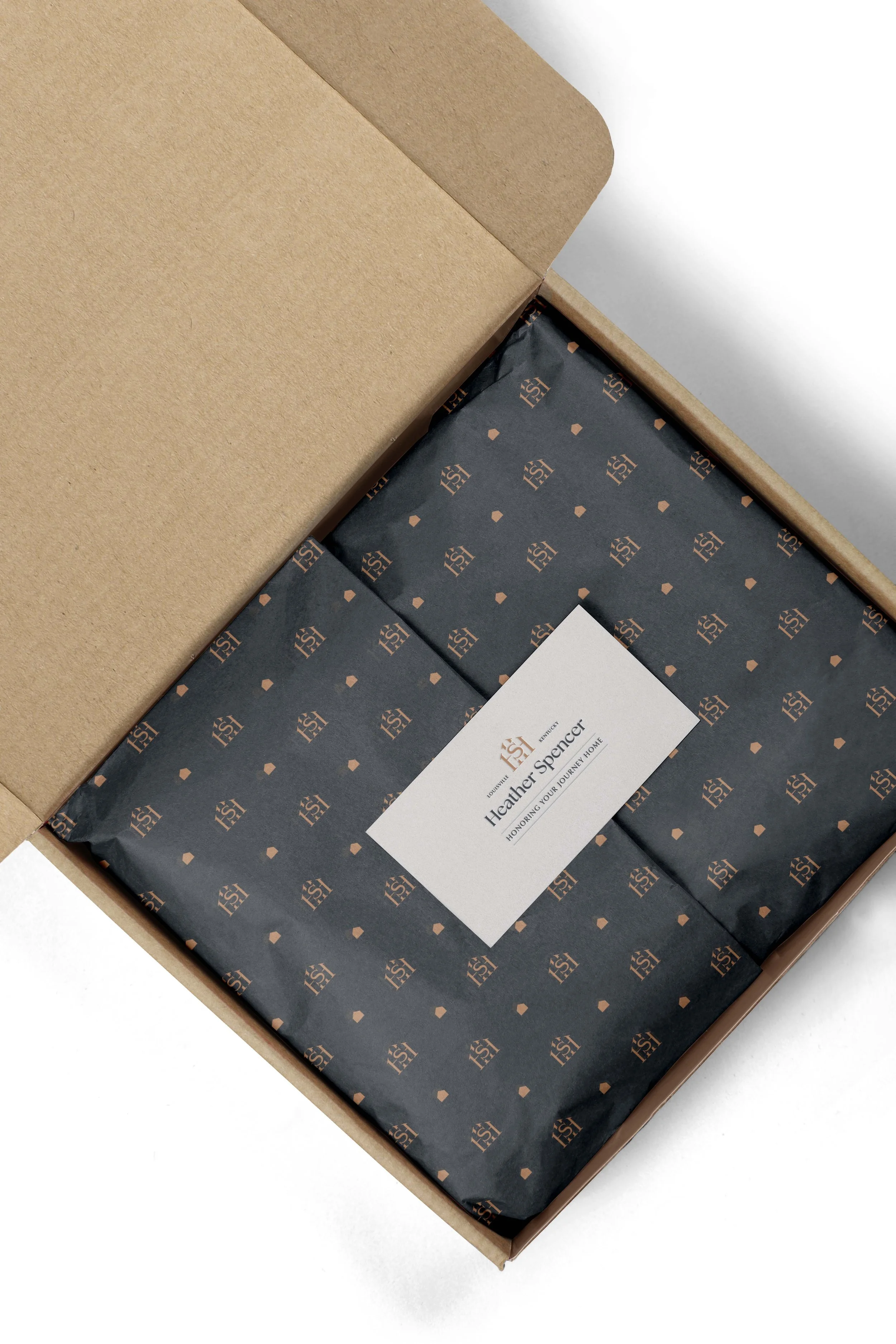 open box containing contents wrapped in branded tissue paper and a Heather Spencer business card on top