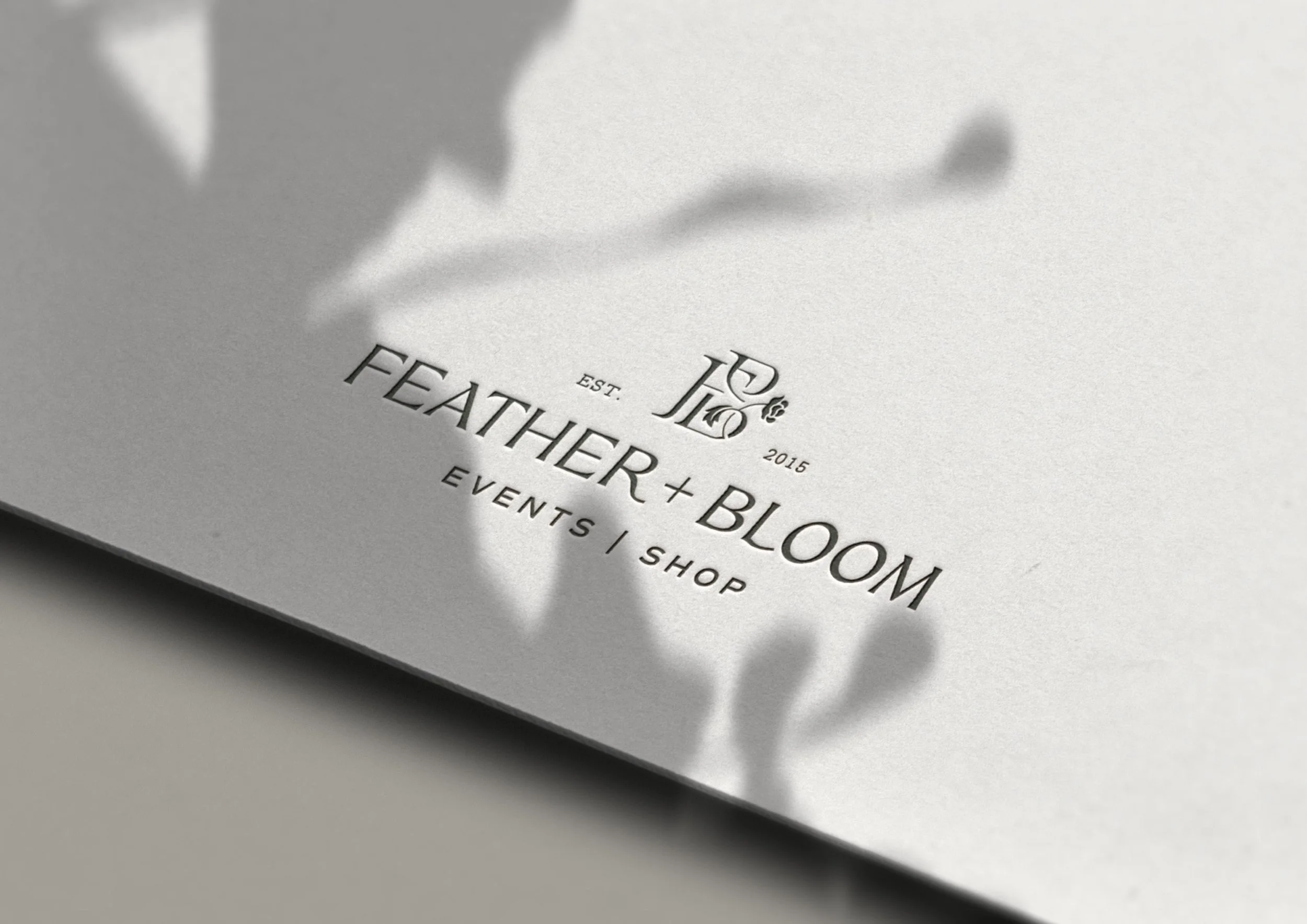 Feather + Bloom logo embossed on cardstock