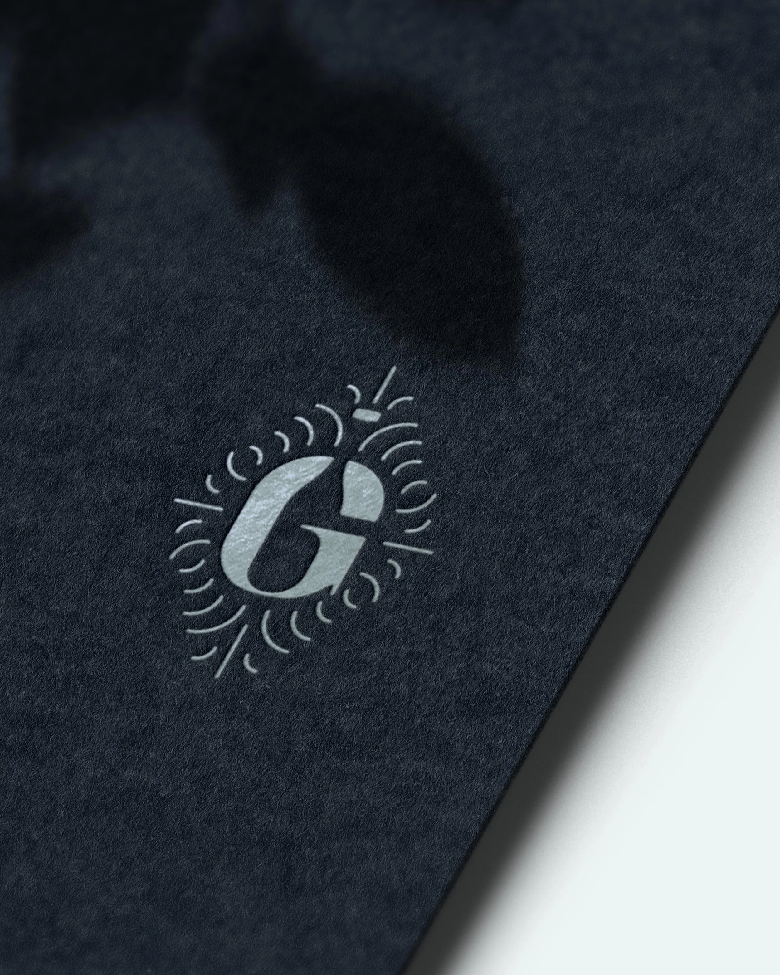 G icon embossed on black cardstock in silver foil