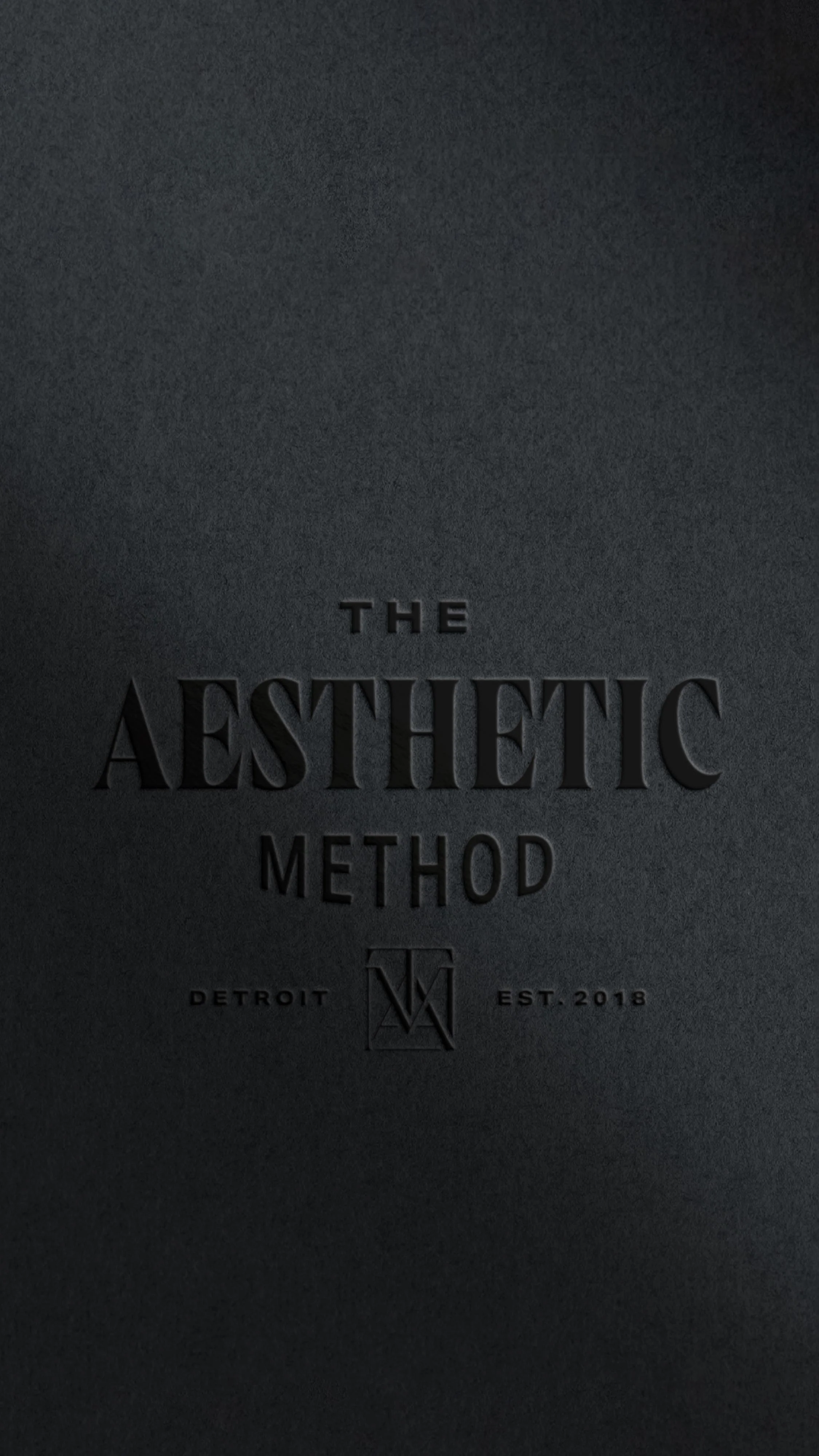 The Aesthetic Method logo embossed on black paper