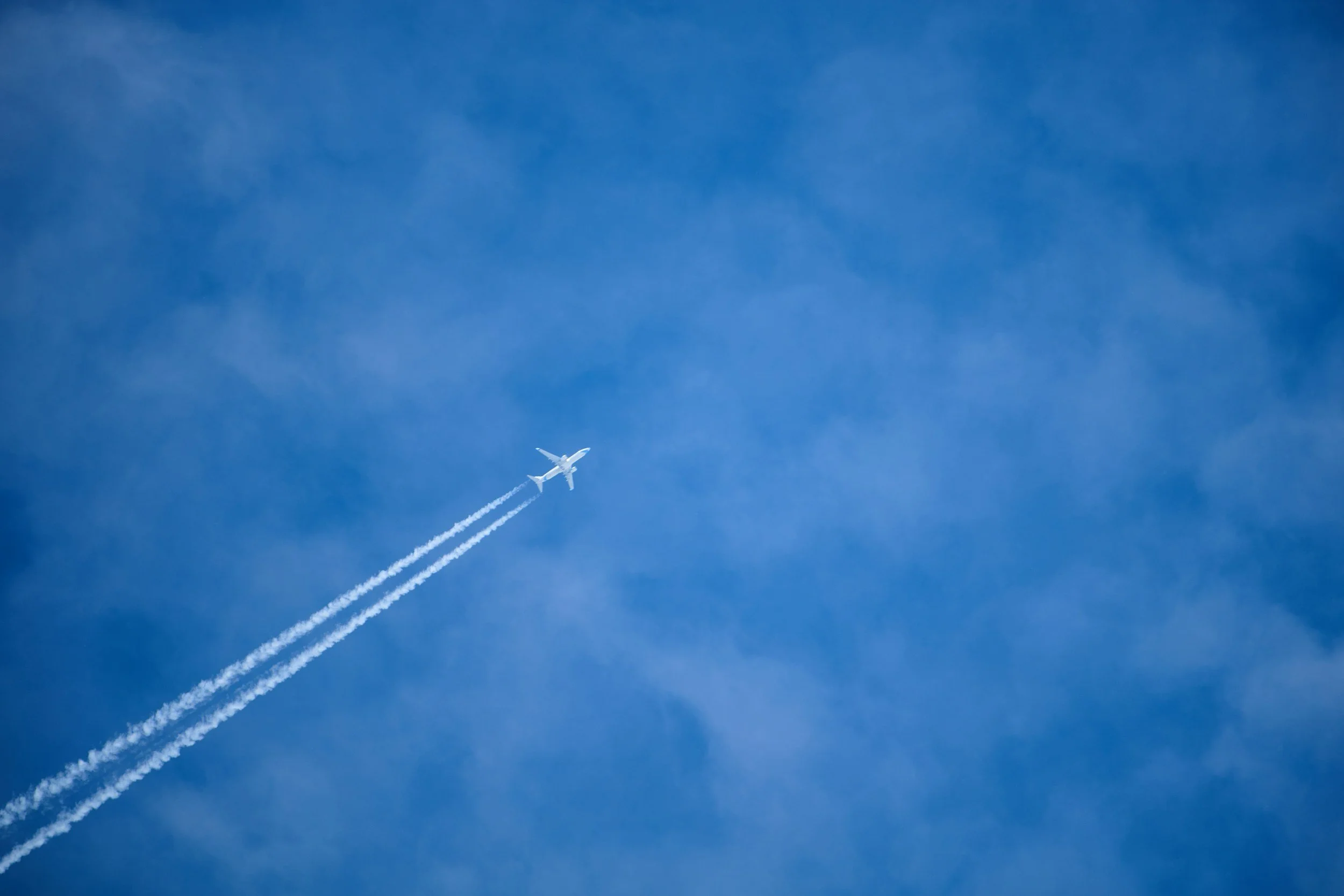 Deux avions volant à haute altitude dans un ciel bleu, laissant des traînées de condensation.