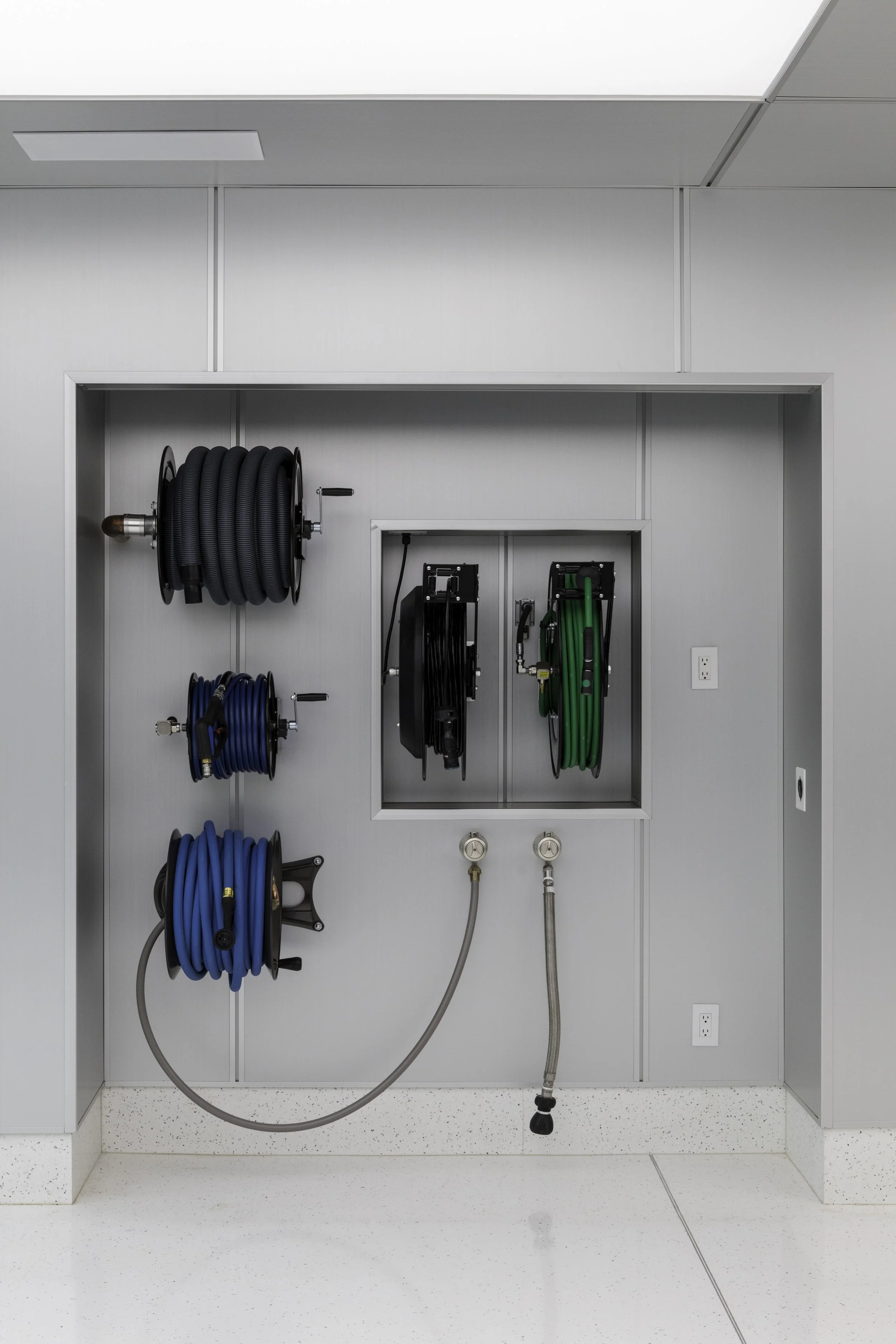 Hospital utility closet with hoses, reels, and meters for medical gas supply.
