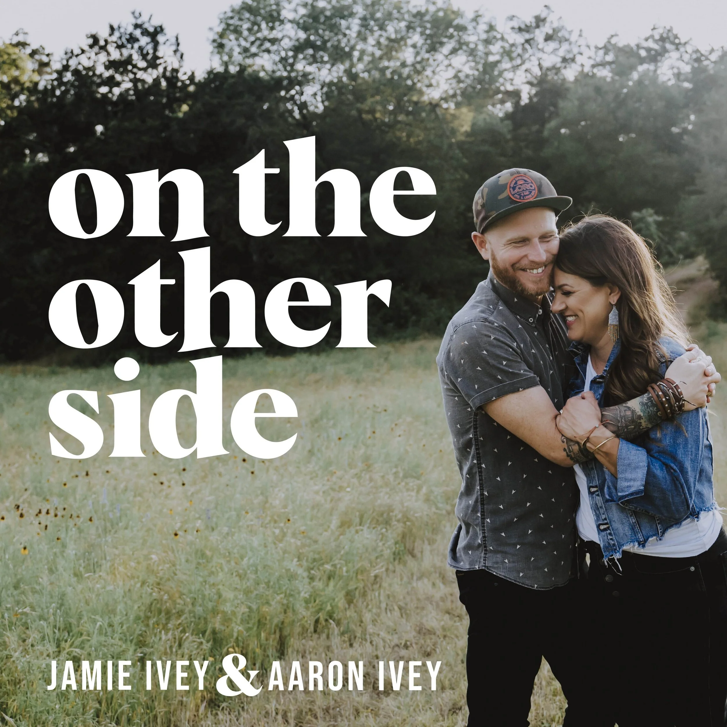 Promotional image for a podcast episode featuring a smiling couple embracing outdoors in a grassy field with trees — podcast Amy Downs appeared on.