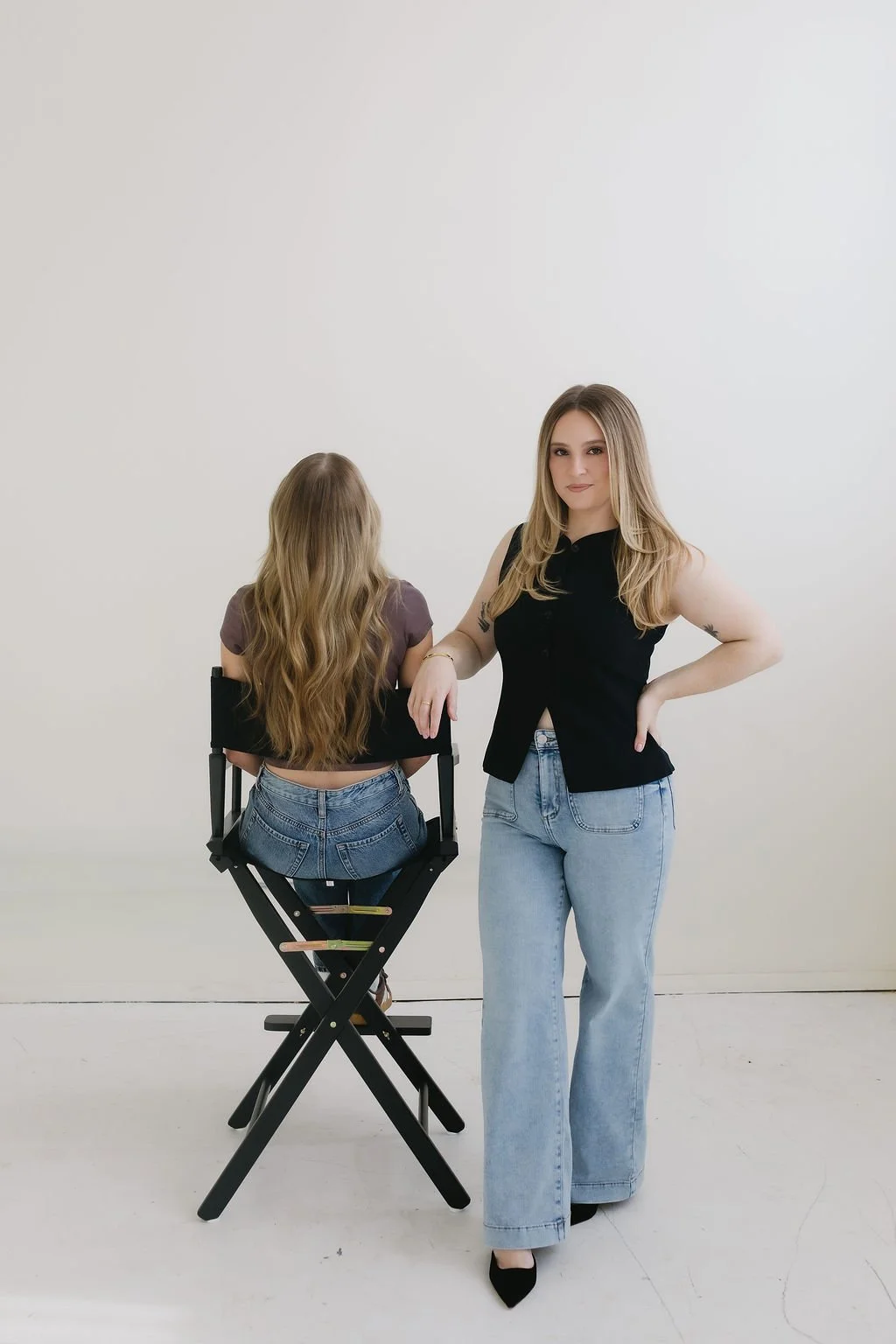 Monica Renee, a Chicago based luxury hairstylist and blonde specialist standing next to her blonde client who is sitting in a directors chair.