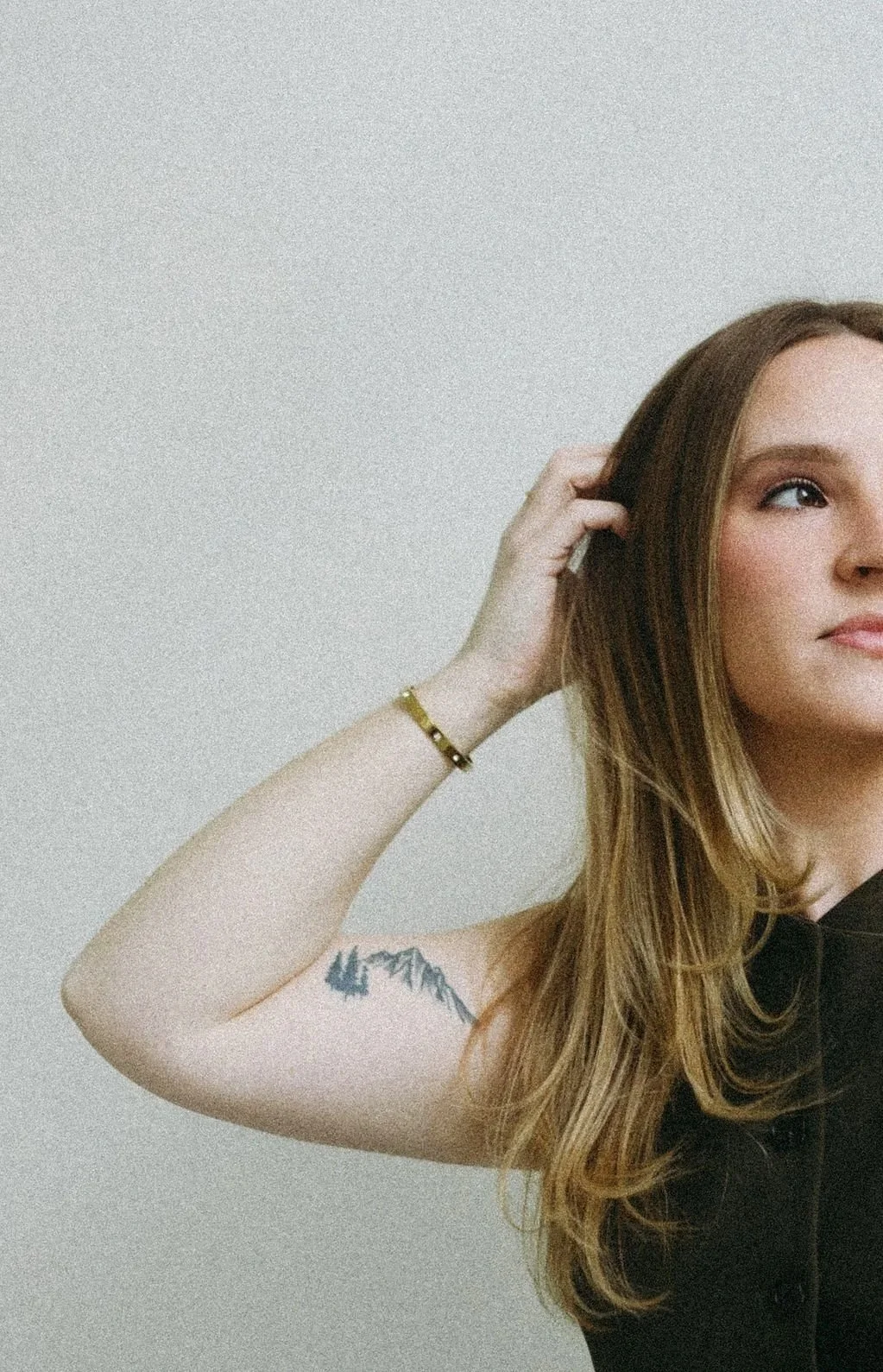 Monica Renee the best hairstylist and blonde specialist in Chicago standing looking off to the side with a slight smile and Hand in her hair.