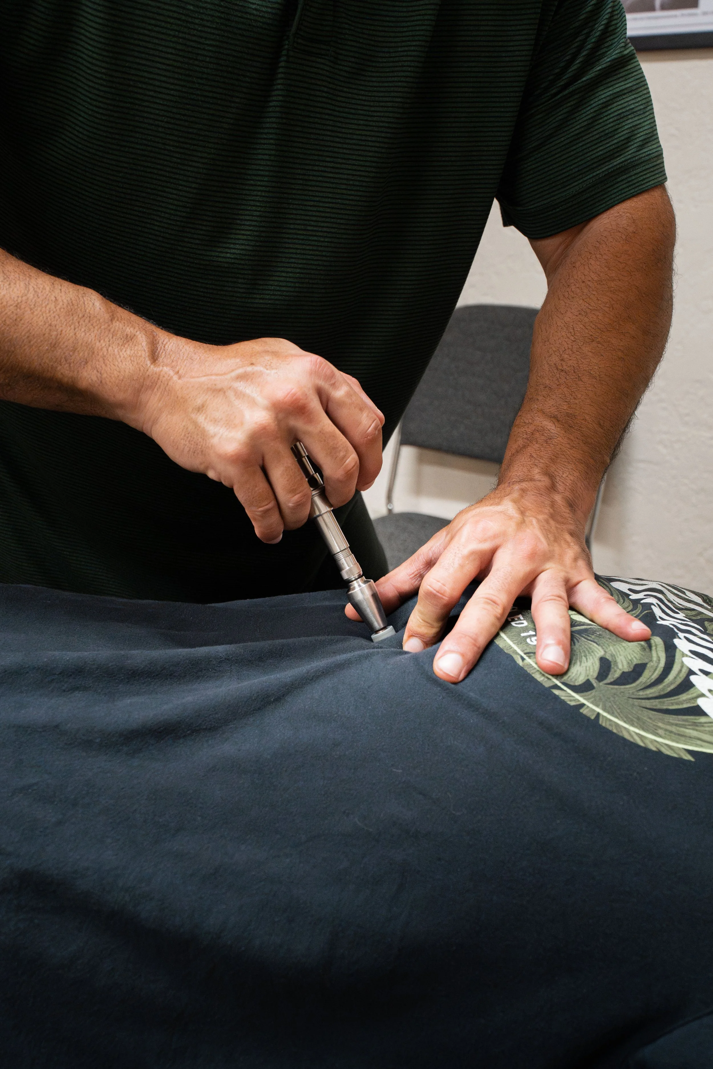 Dr. Kevin Perrino performing a chiropractic adjustment using the Activator Method at the Head and Neck Center of Hawai‘i.