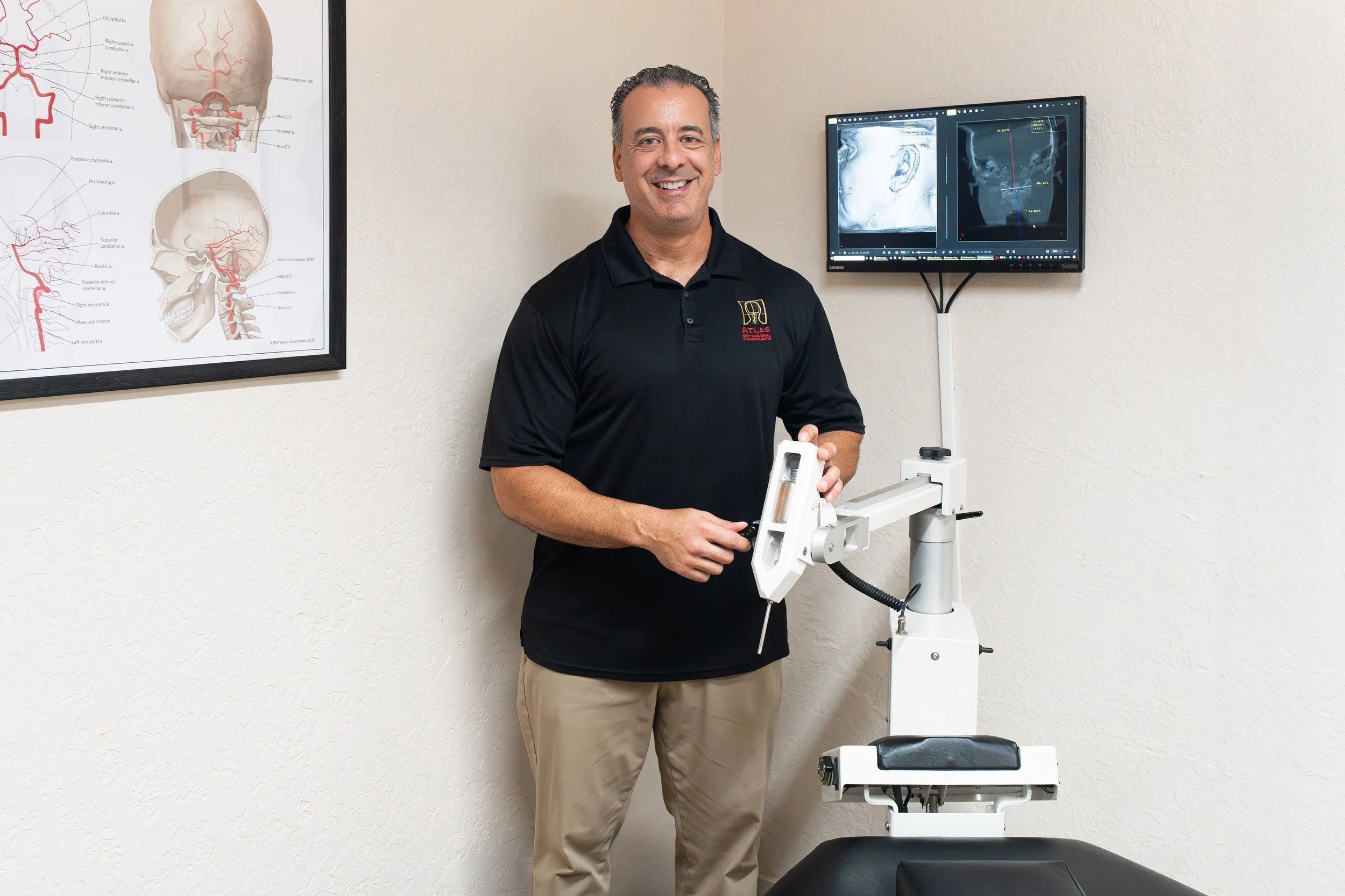 Dr. Kevin Perrino, D.C., standing beside the Atlas Orthogonal instrument at the Head and Neck Center of Hawai‘i in Kona.