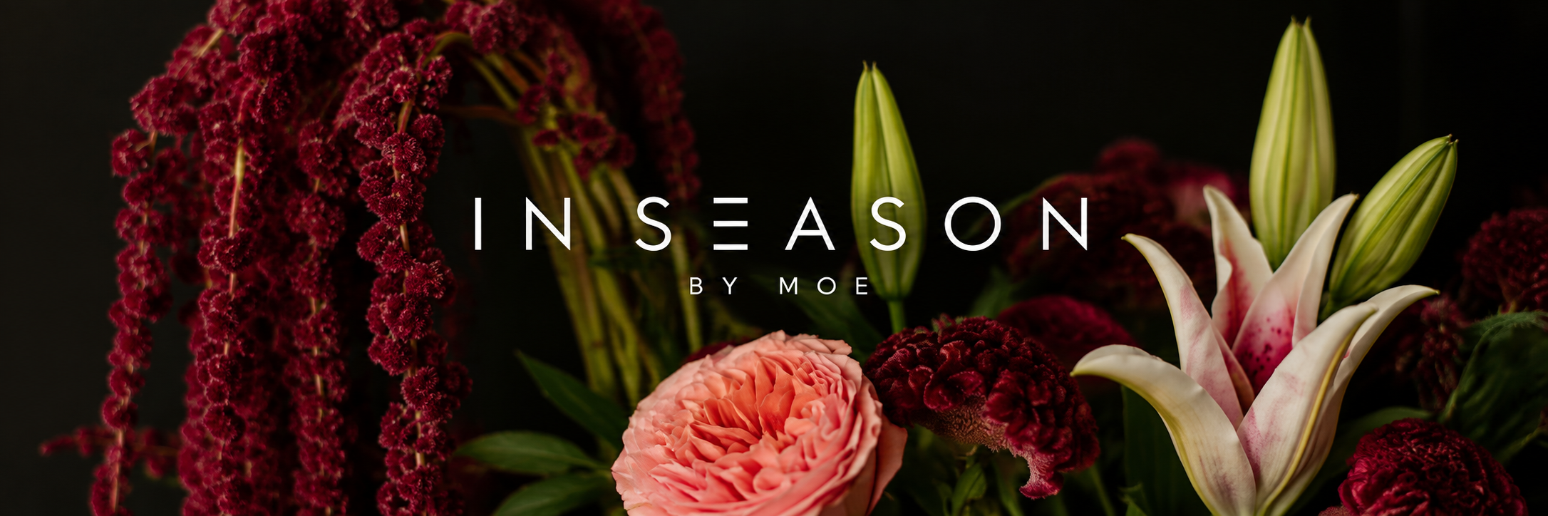 A dark background with pink lilies, burgundy amaranthus, and pink velvety roses, with the words 'In Season by Moe' overlayed. charlotte florist.