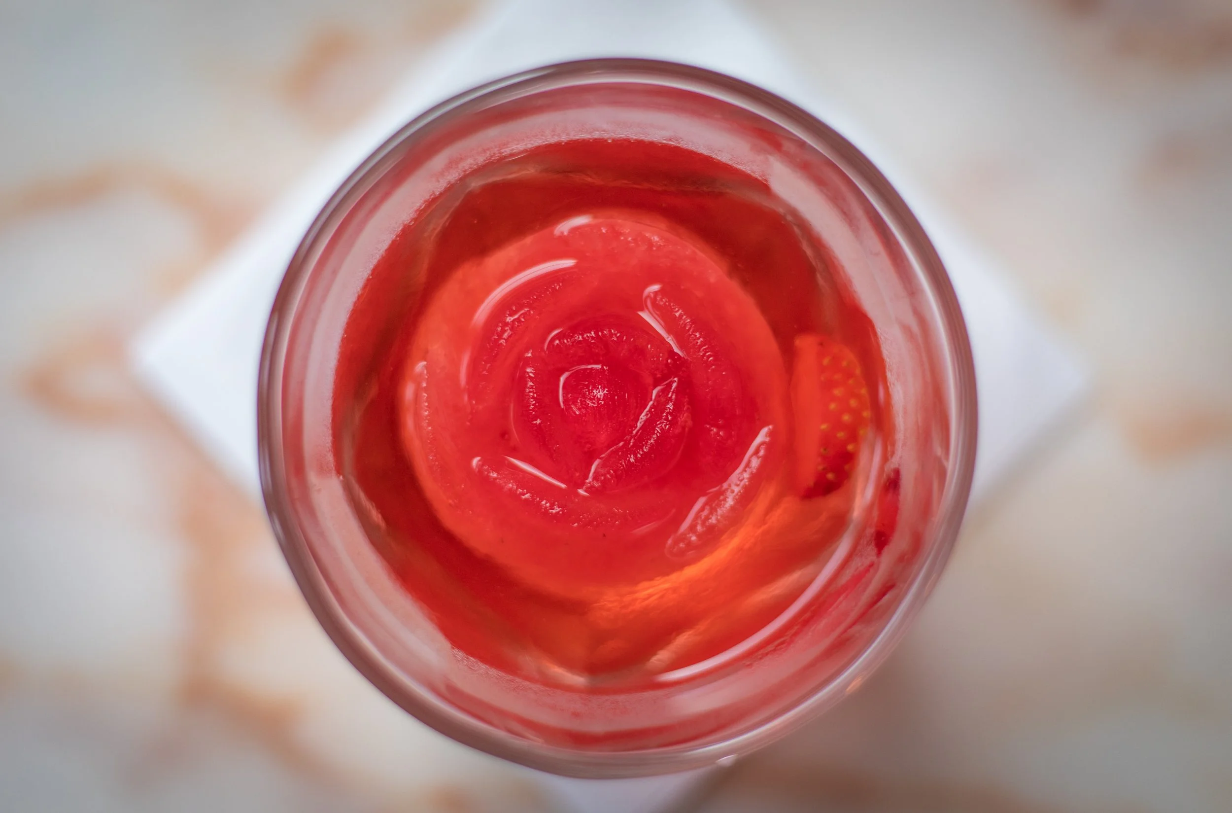 Top-down view of a glass with pink strawberry-flavored drink and strawberry slices inside.