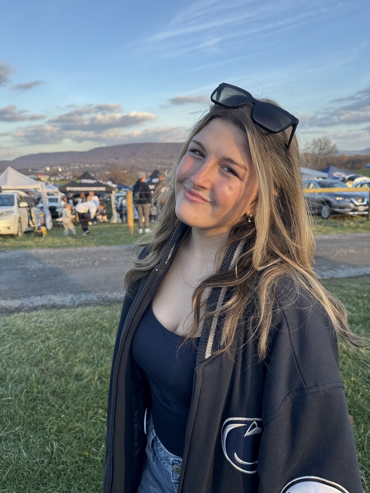 A woman smiling at a football game in a stadium packed with spectators at night.