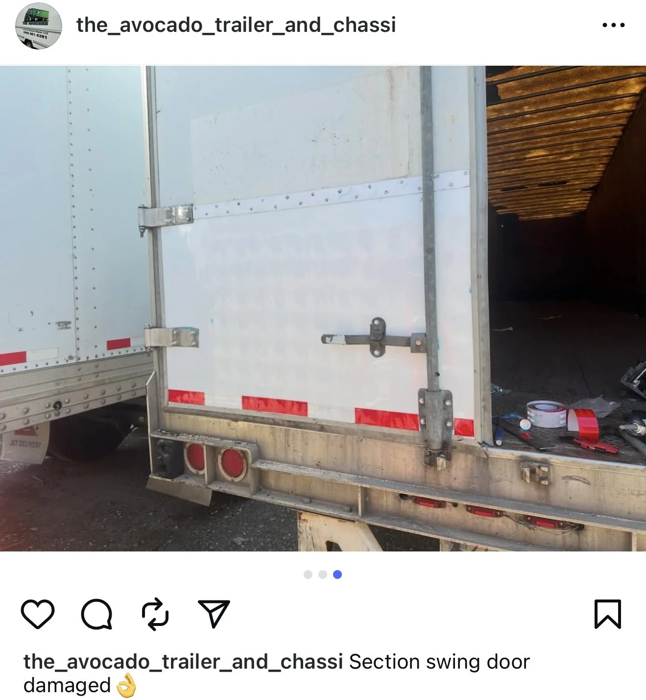 Close-up of a section swing door on a white trailer, showing damage on the door hardware and frame.
