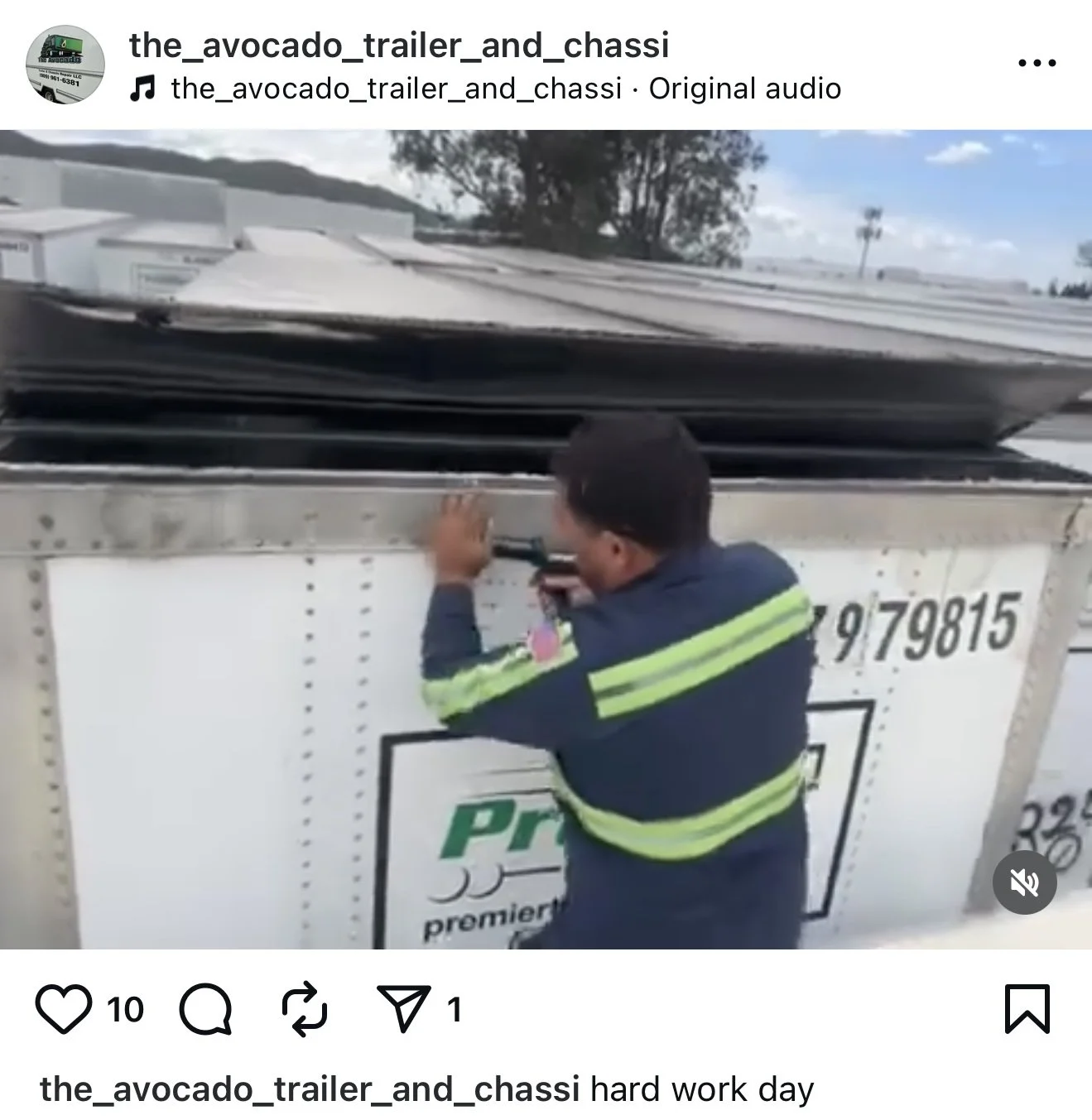 A worker fixing or inspecting the side of a large trailer truck on a workday.