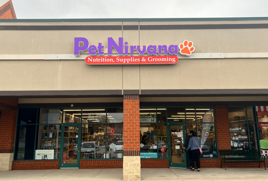 Exterior of Pet Nirvana store with purple sign and paw logo, offering nutrition, supplies, and grooming.