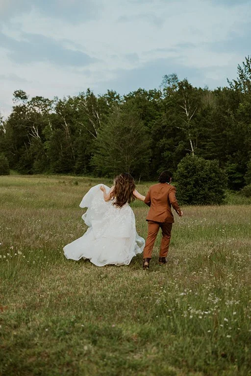 A couple run in a field during the Marquette Michigan Wedding