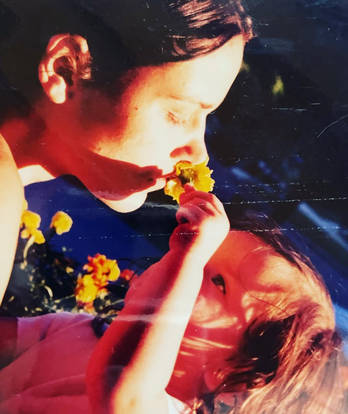 1.5 year old Eva Luna Ortiz appears giving her mother Laura Salwet an orange flower to smell. The sunset illuminates their face.