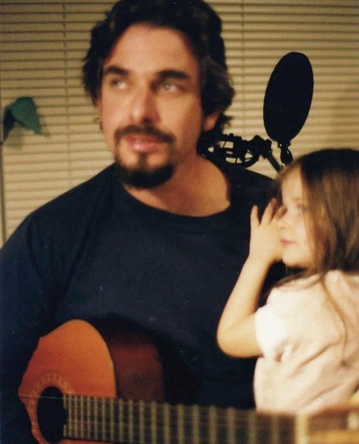 2 year old Eva Luna Ortiz sits on father Ramon Ortiz's lap as he plays the acoustic guitar