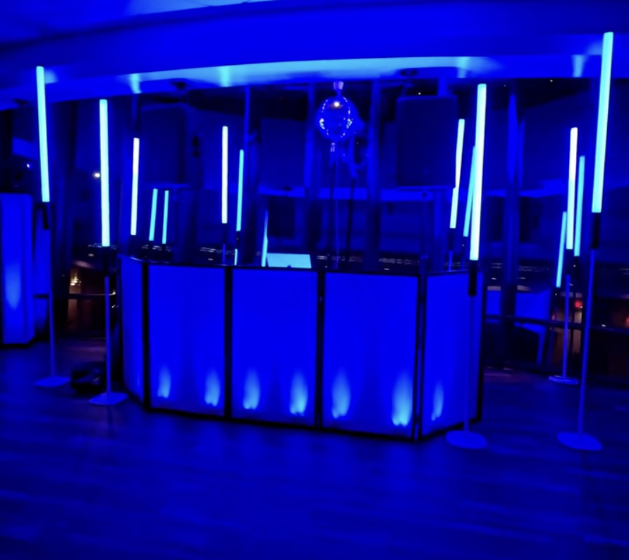 Modern wedding DJ booth with blue LED lighting and uplights by Versamix Music in Savannah.