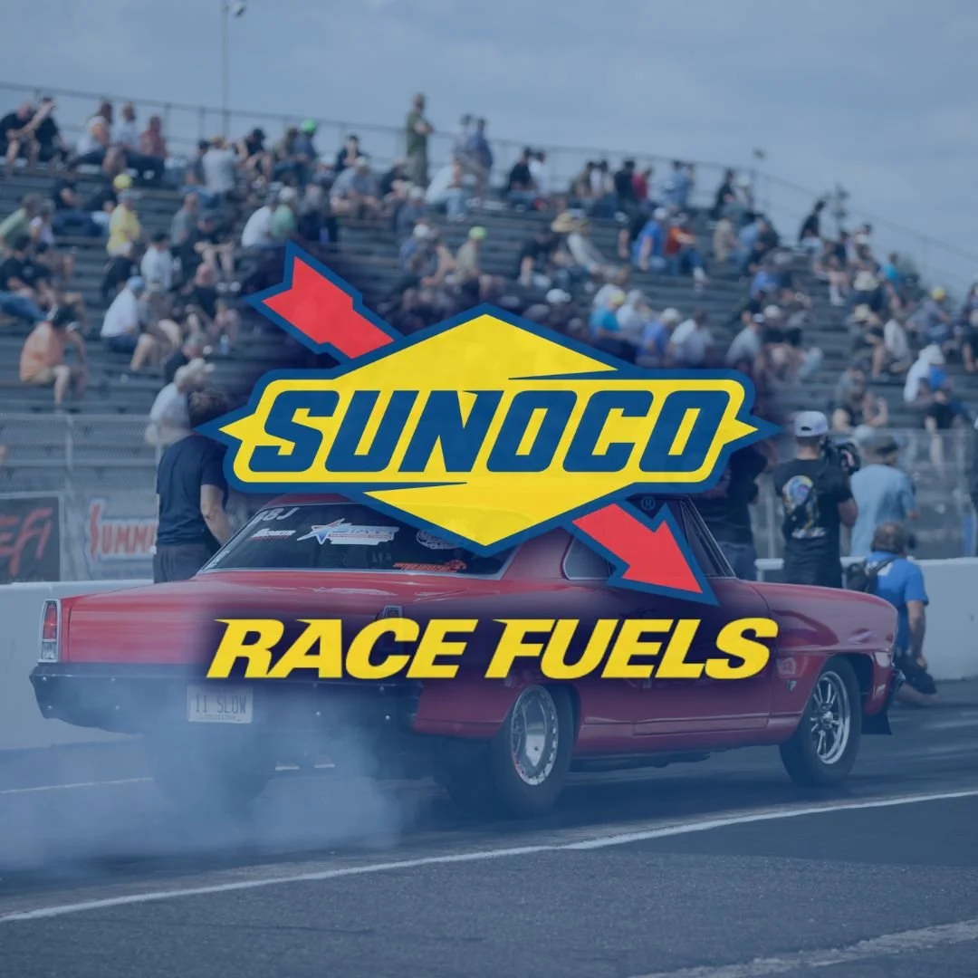 A red race car performing burnouts on a racetrack with spectators in the stands. Overlaid with a graphic featuring the Sunoco logo and the text "Race Fuels."