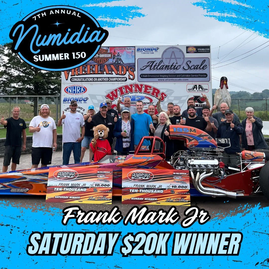 Group of people celebrating at a drag racing event, with a race car, large checks for $10,000, and a person in a bear mascot costume. The event is the 7th annual NUmidia Summer 150, and the winner is Frank Mark Jr, who won $20,000 for Saturday's race