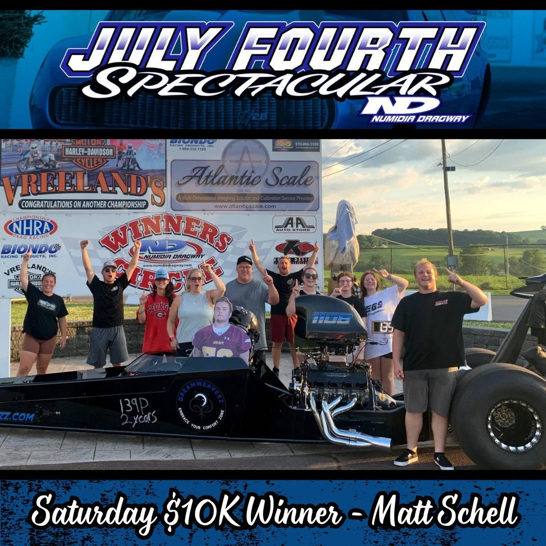 Group of people celebrating around a race car at Numidia Dragway after winning a $10,000 prize on Saturday, with a large sign behind them displaying race event sponsors and winners.