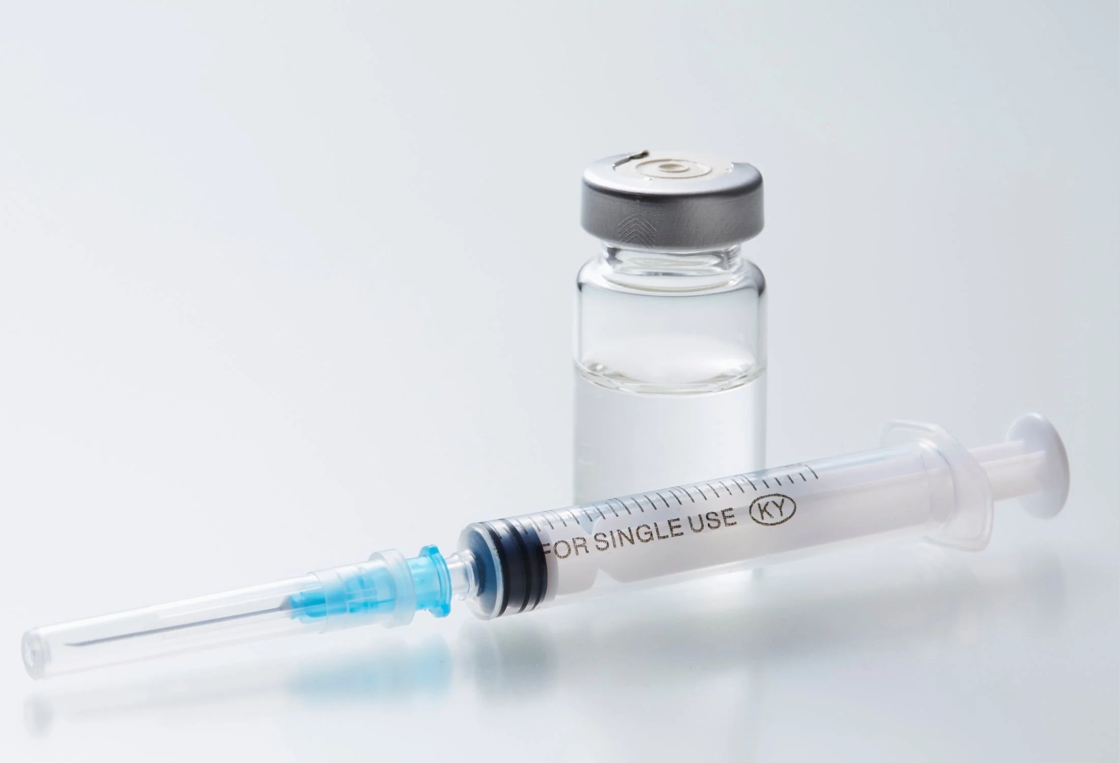 syringe on a table next to a bottle of clear liguid
