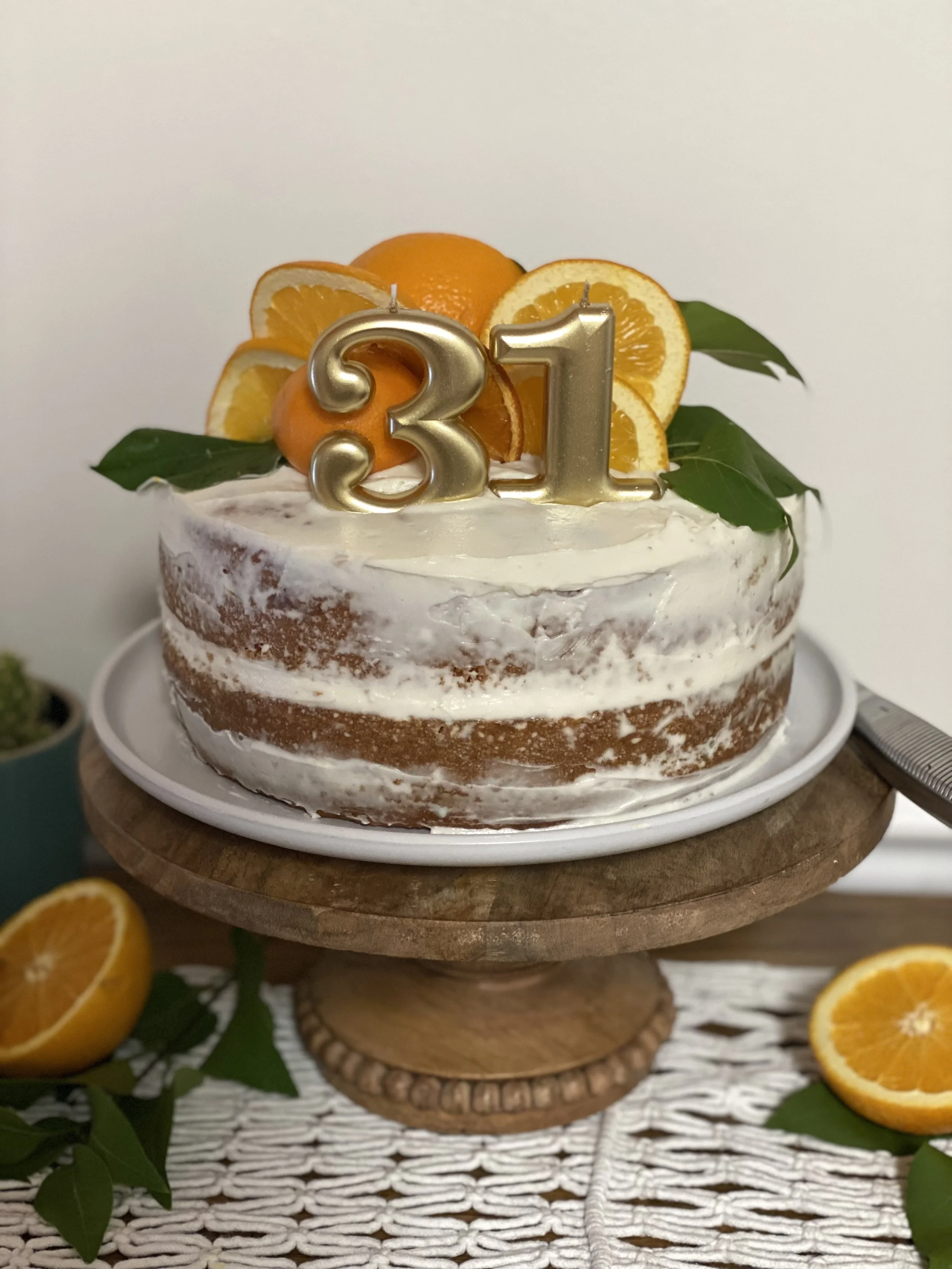 Celebration cake decorated with orange slices, green leaves, and gold number candles displaying '31'.