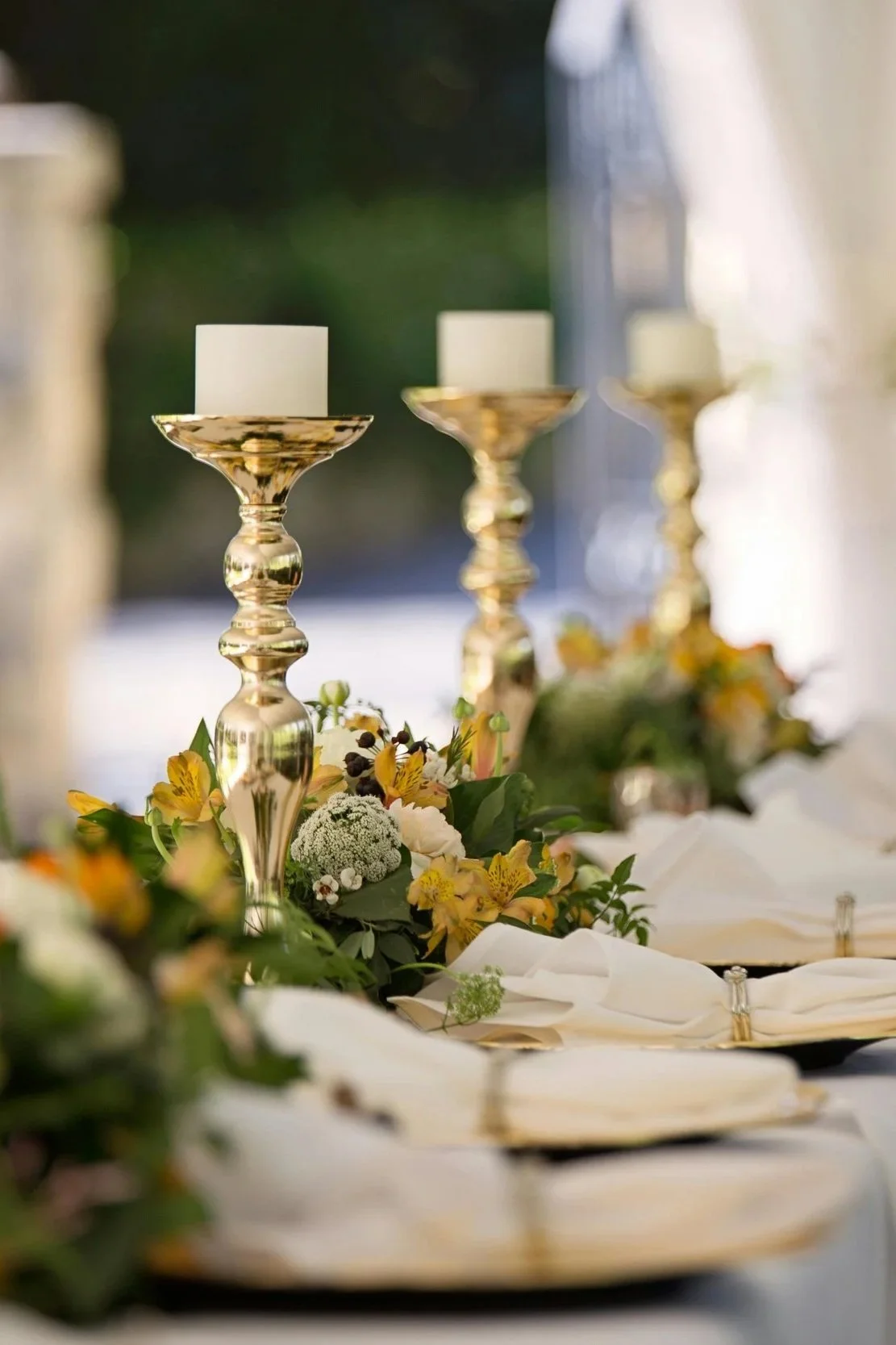 Elegant table setting with gold candlesticks and floral arrangements.