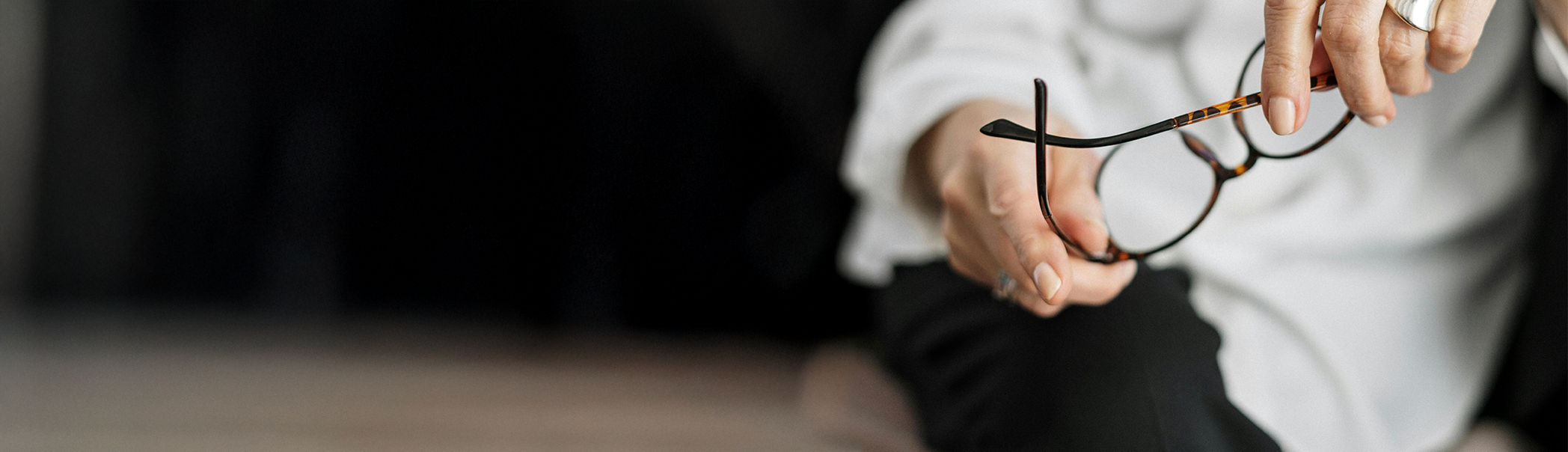 Person holding and examining a pair of eyeglasses.