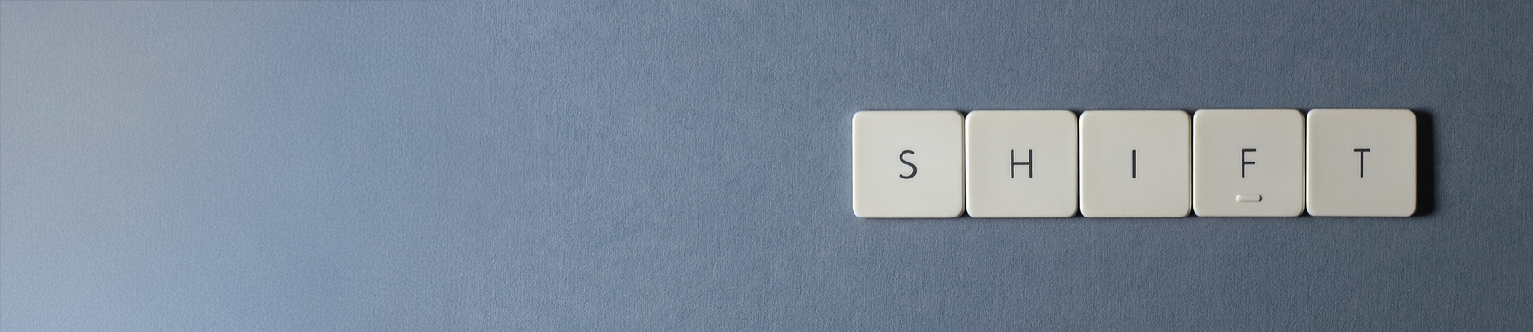 Close-up of a blue surface with white square keys spelling 'SHIFT' on the right side.