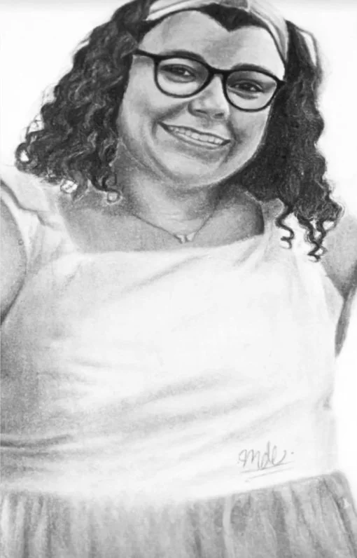 Black and white portrait of a woman with curly hair, glasses, and a wide smile, wearing a light-colored top.