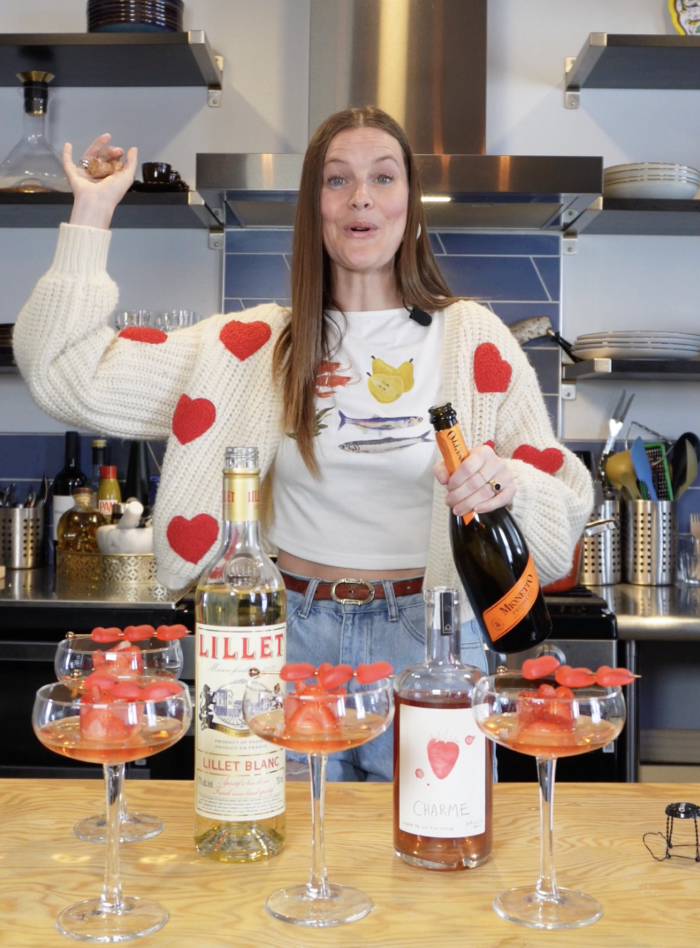 Woman celebrating Valentine's Day with heart-themed drinks and wine in a kitchen.