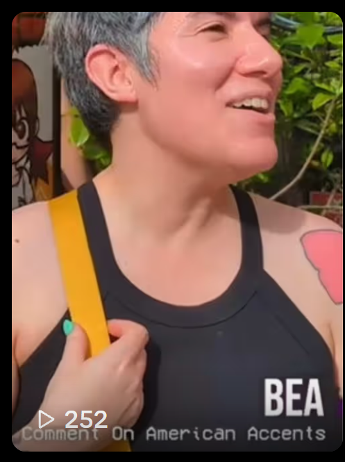 Still from a video of Bea, in a black tanktop, looking off camera and smiling.